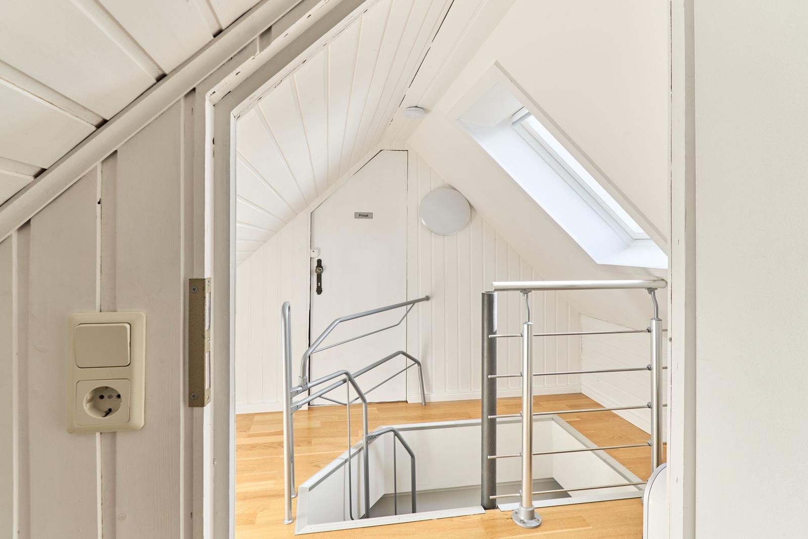 Dachgeschoss mit Treppe und Dachfenster. Holzboden und weiße Wände.