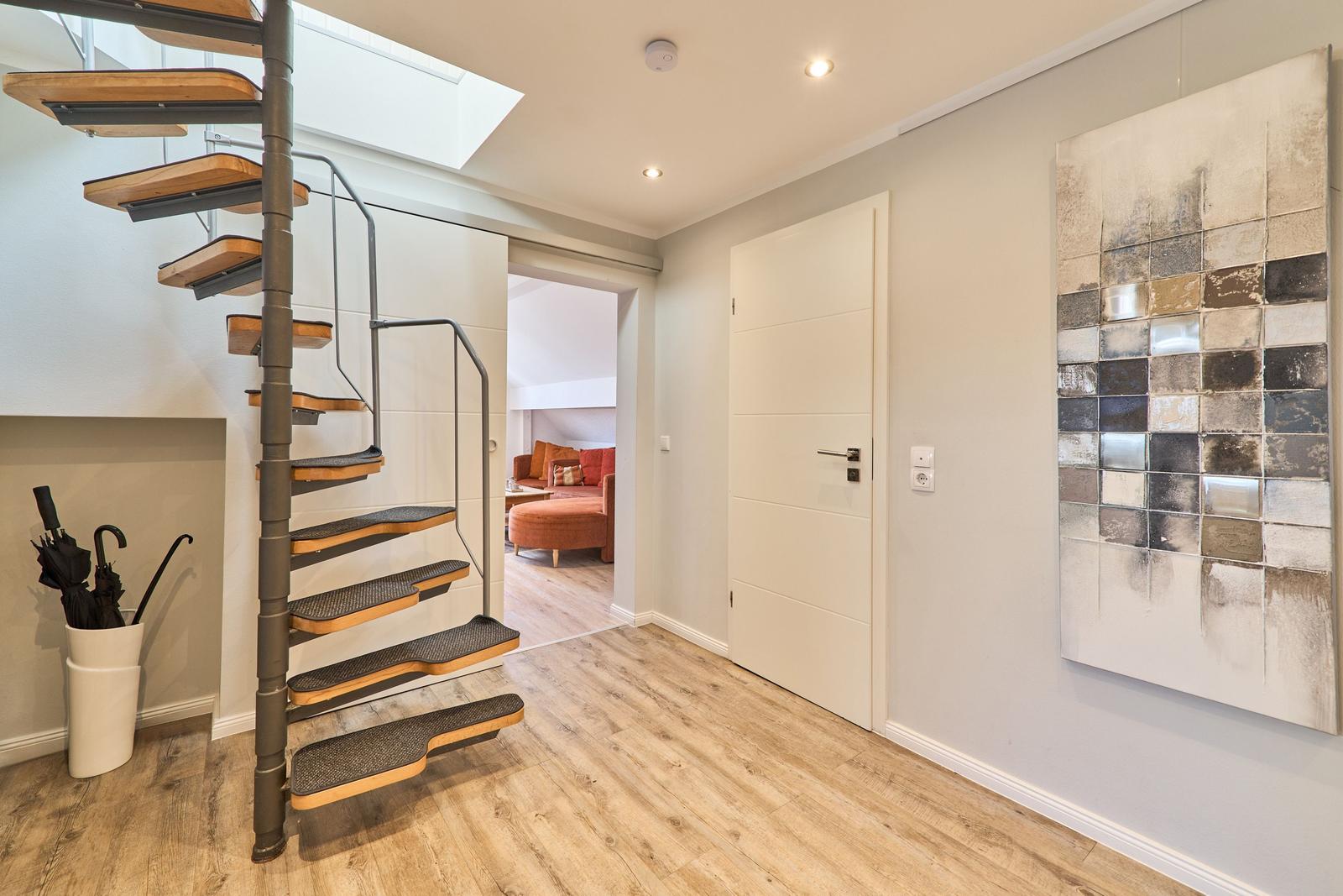Haus mit Wendeltreppe, Holzboden und Wandbild. Durchgang zum Wohnzimmer mit Sofa.