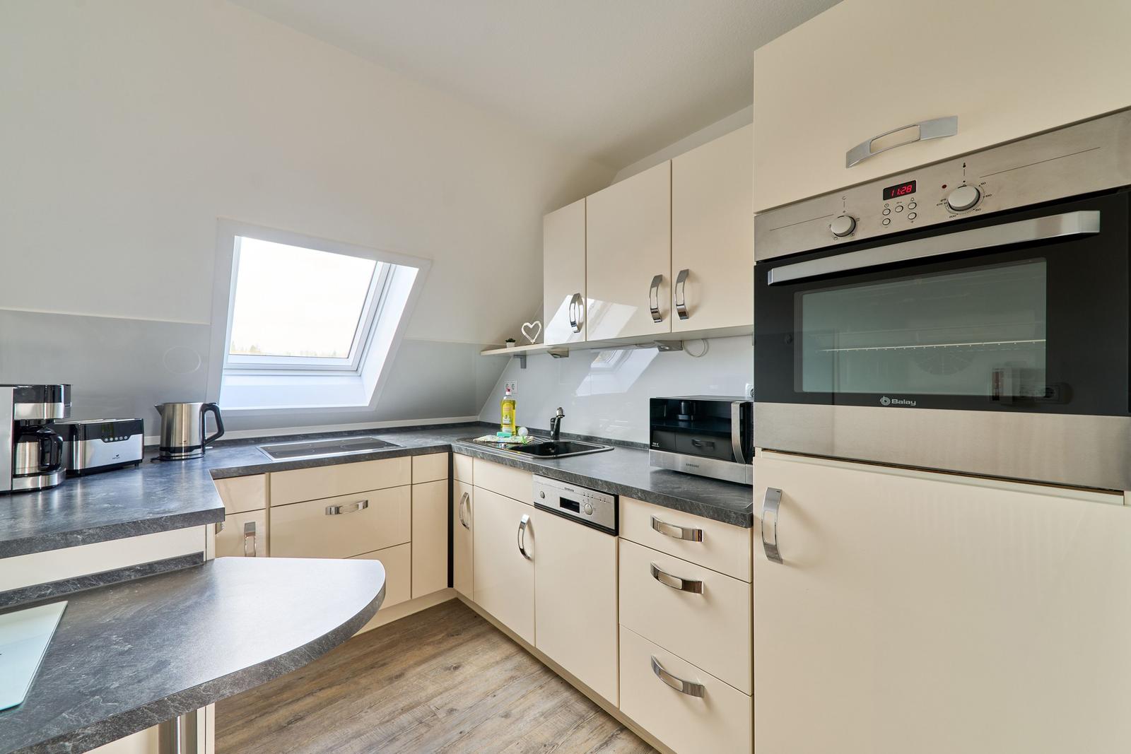 Küche mit Schränken, Arbeitsfläche und Fenster