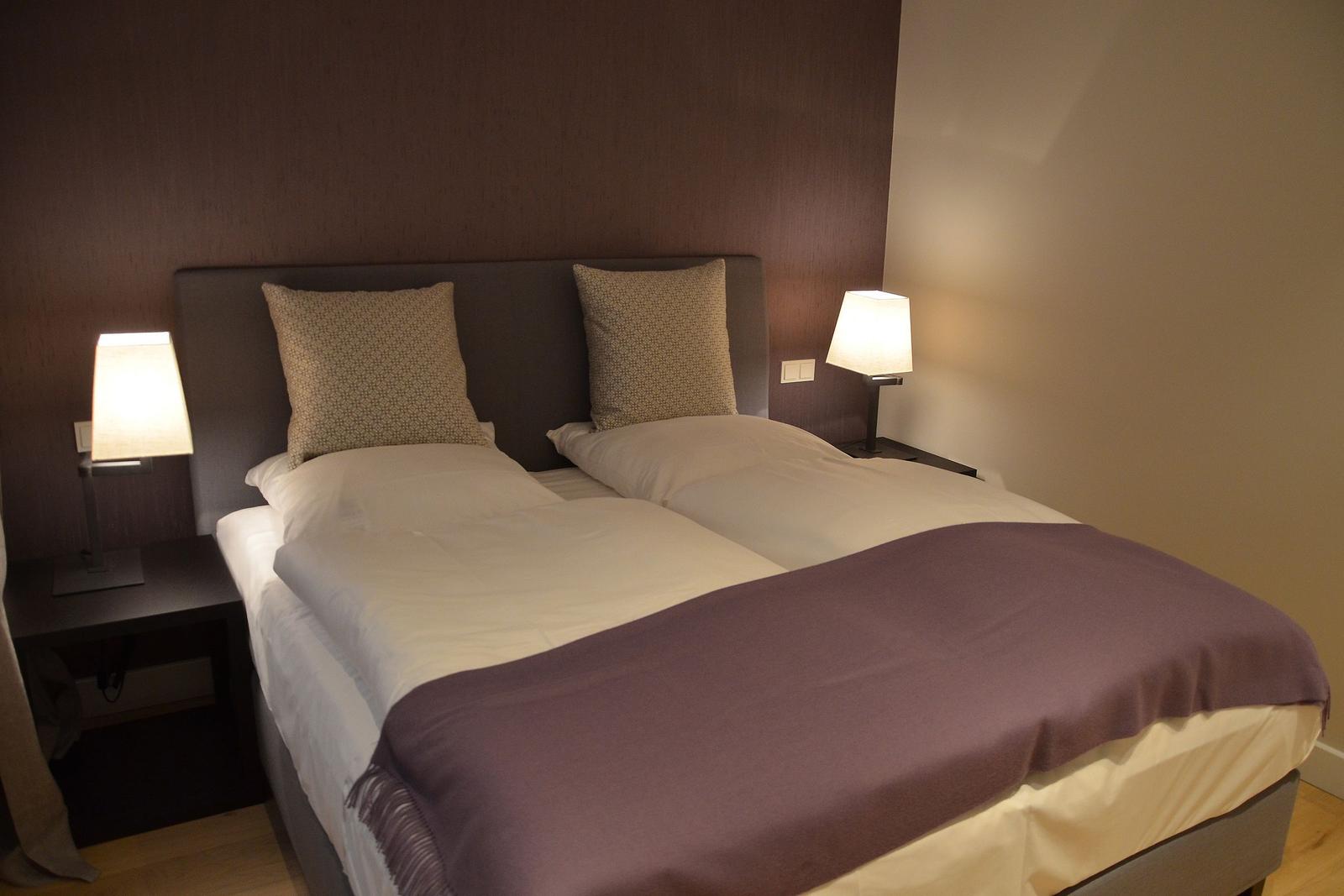 Schlafzimmer mit Doppelbett, zwei Nachttischen und Lampen.