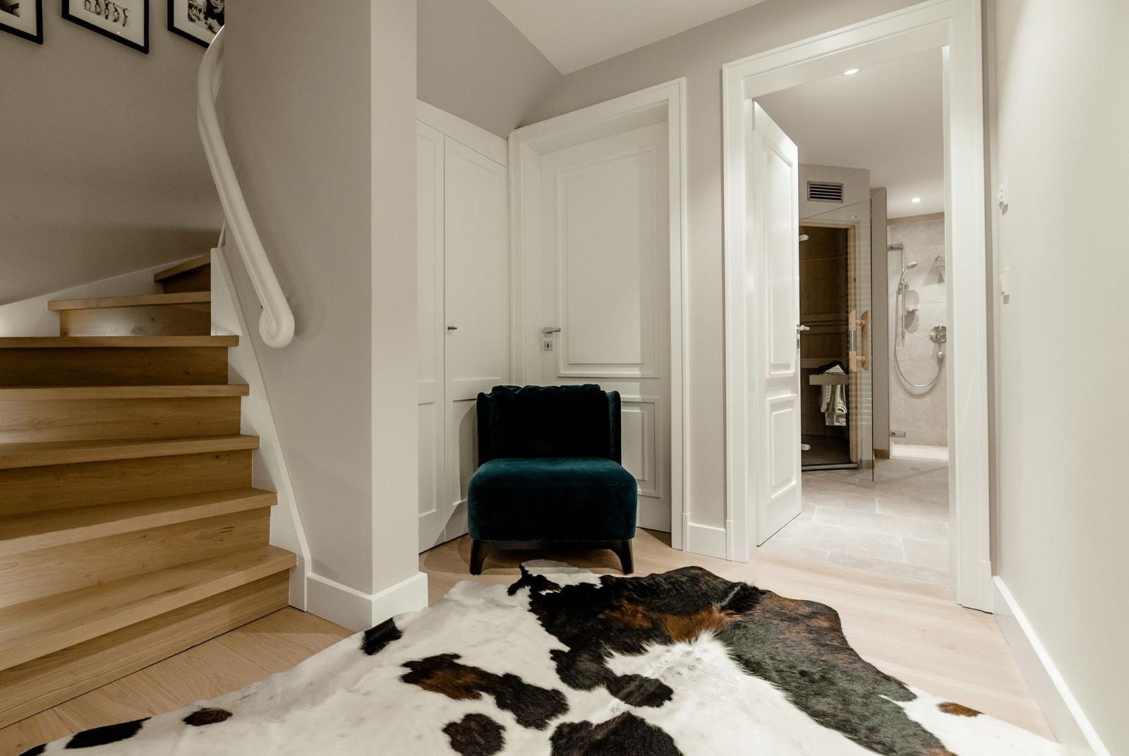 Hausflur mit Treppenhaus, Sitzgelegenheit und Blick in die Dusche.