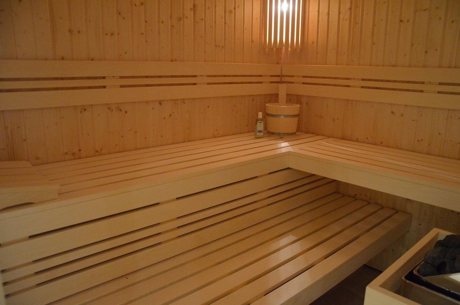 Sauna mit Holzbänken, Eimer und Flasche