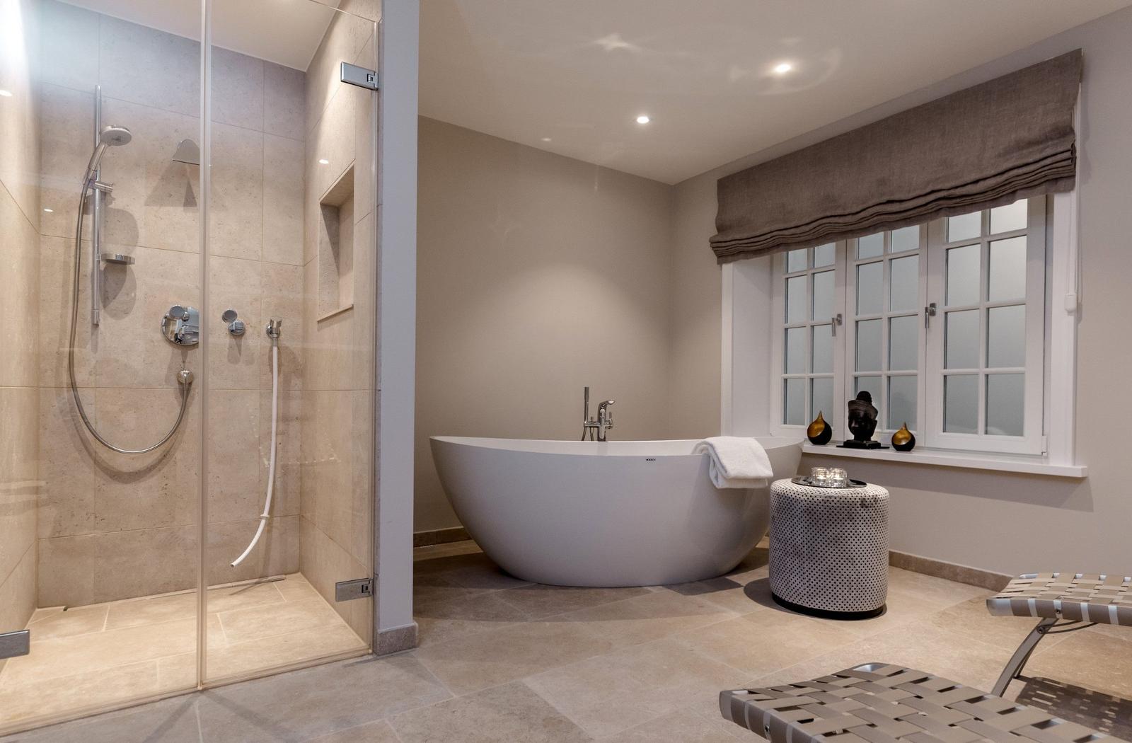 Dusche mit Glaswand und freistehende Badewanne unter Fenster