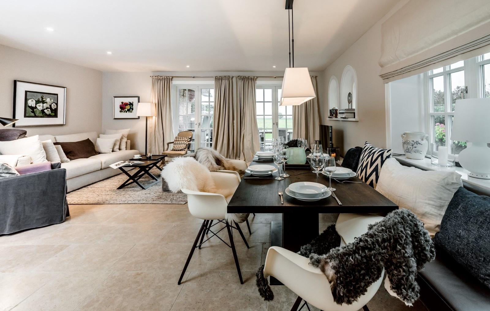 Wohn- und Essbereich mit Tisch, Stühlen, Sofa und Fenstern.