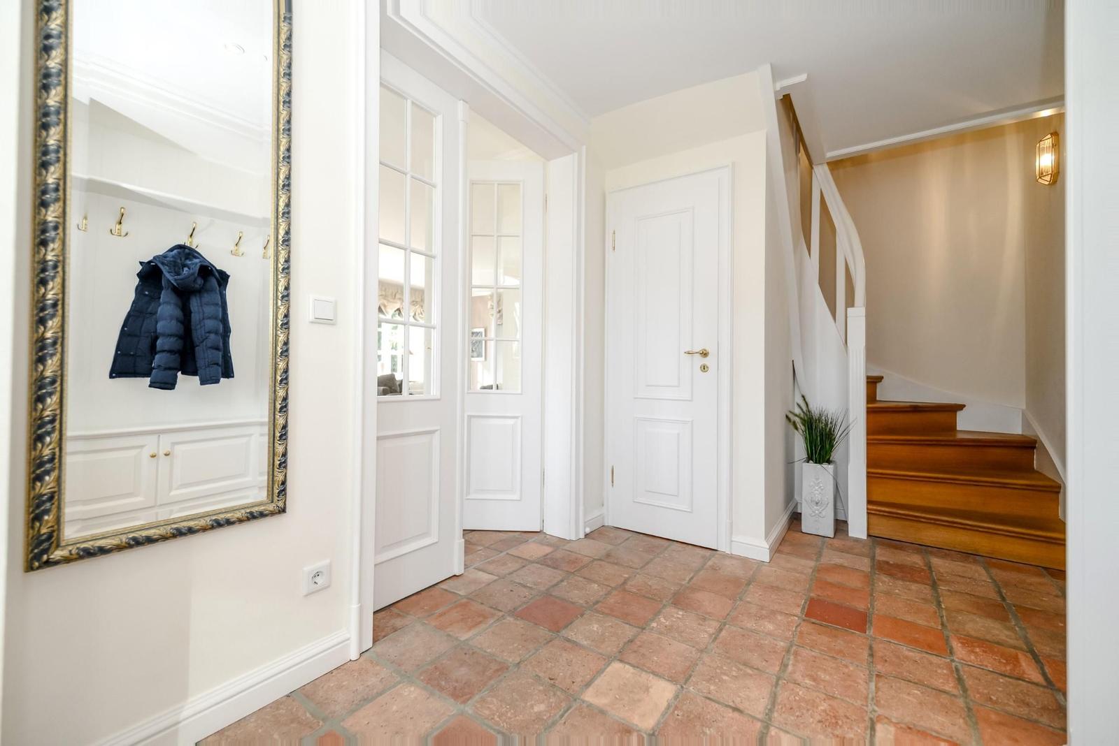 Eingangsbereich mit Spiegel, Garderobe und Holztreppe.