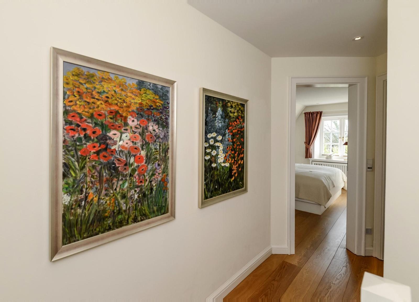 Flur mit zwei Gemälden und Blick in Schlafzimmer mit Bett und Fenster.
