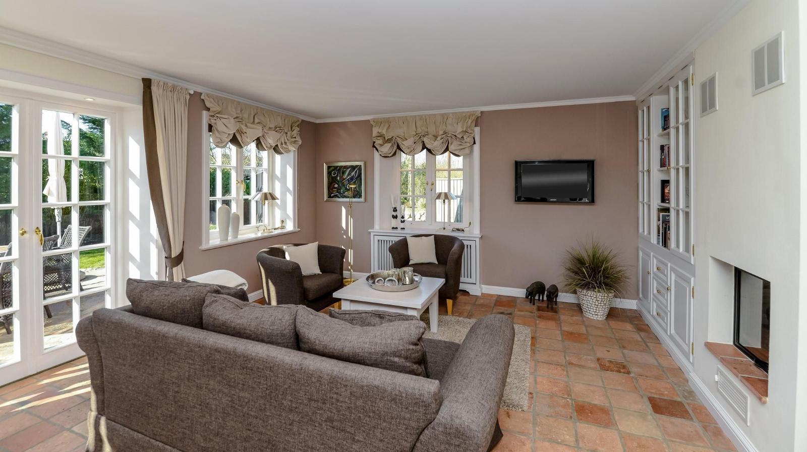 Wohnzimmer mit Sofa, Sesseln, Fernseher und Kamin