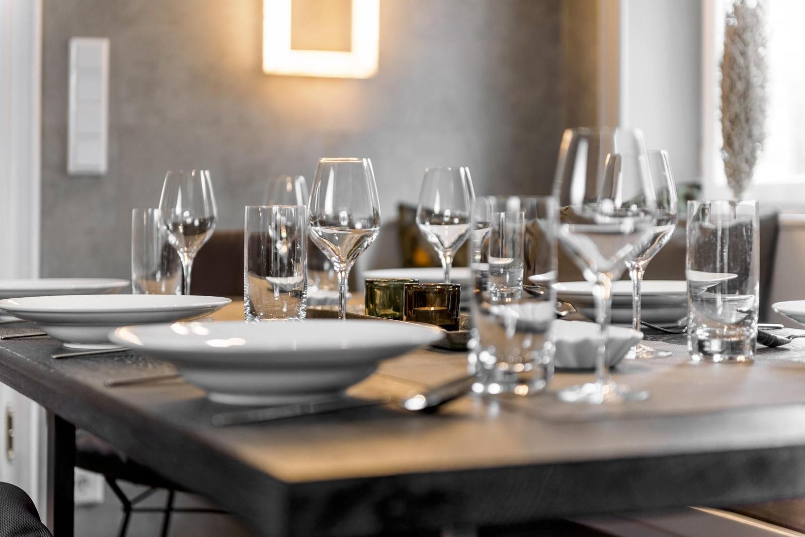 Gedeckter Esstisch mit Gläsern und Tellern.