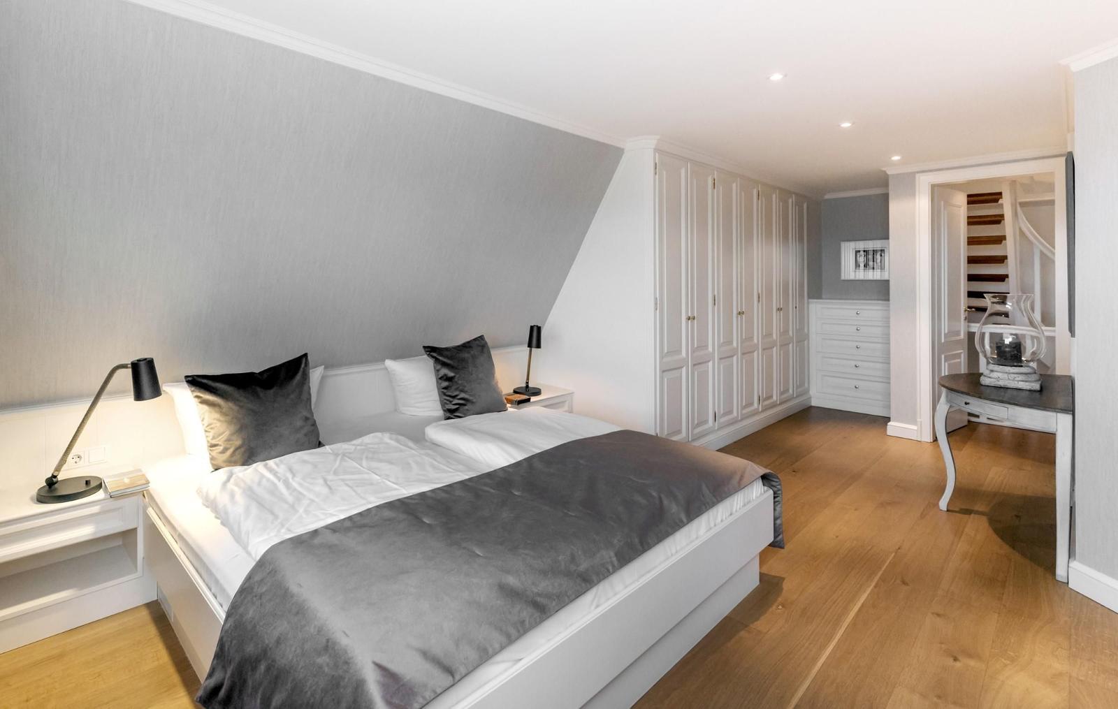 Schlafzimmer mit Doppelbett, Kleiderschrank und Holzboden.