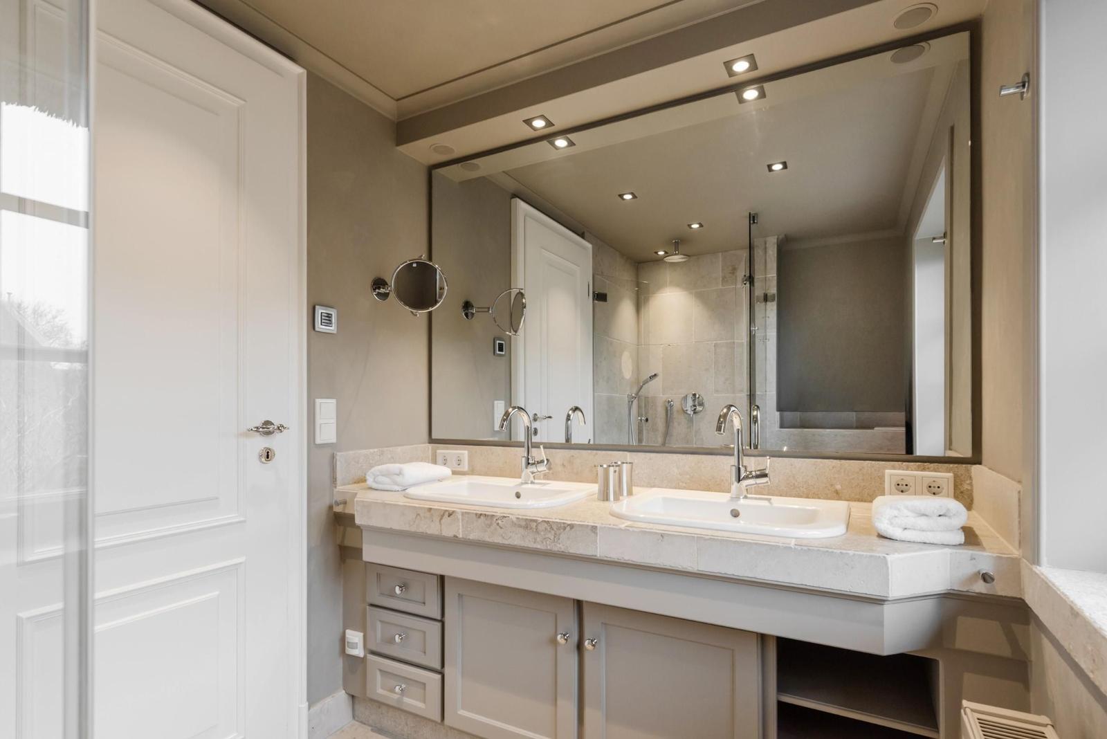 Badezimmer mit Doppelwaschbecken, Spiegel und Dusche