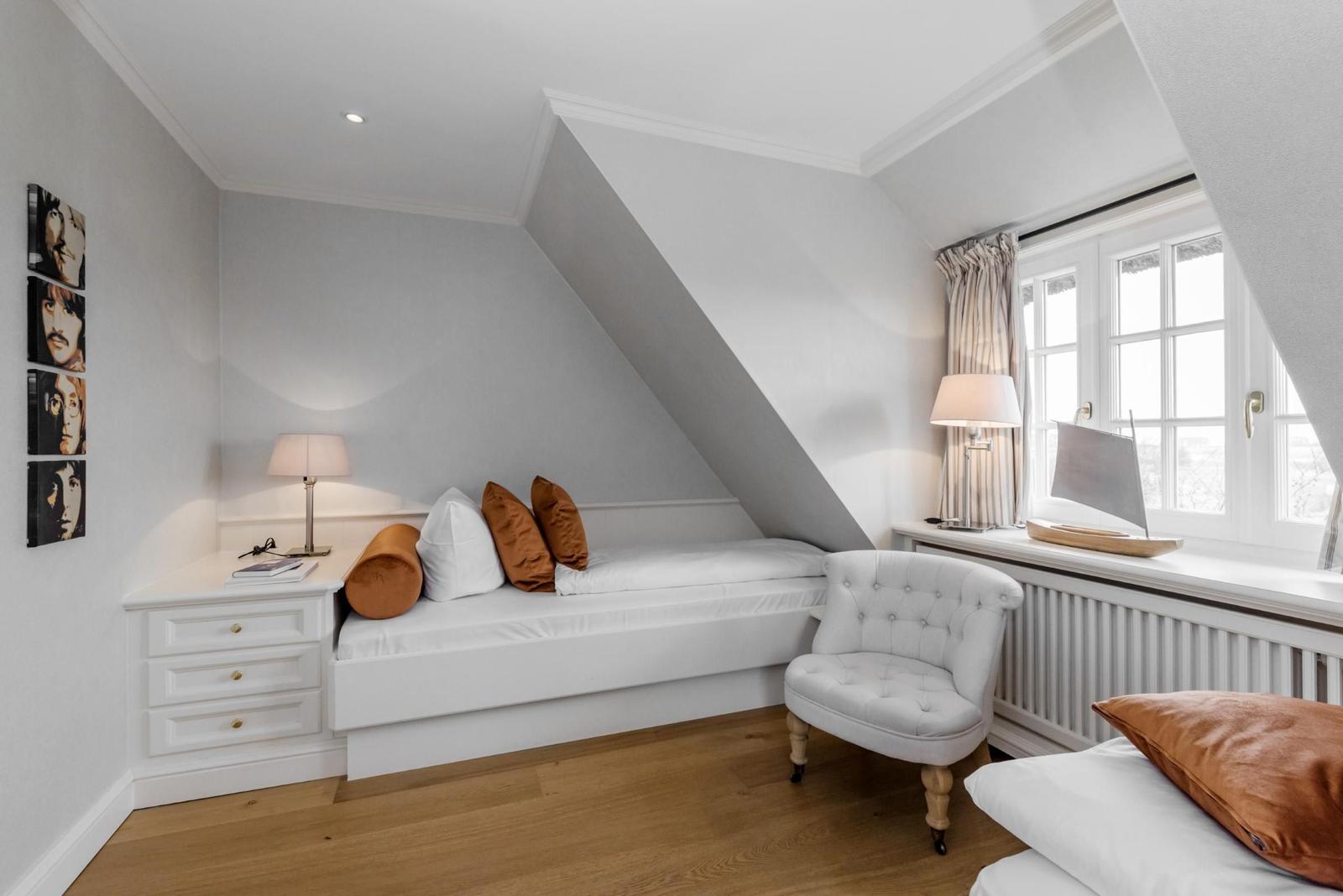 Schlafzimmer mit Dachschrägen, Bett, Stuhl und Fenster.