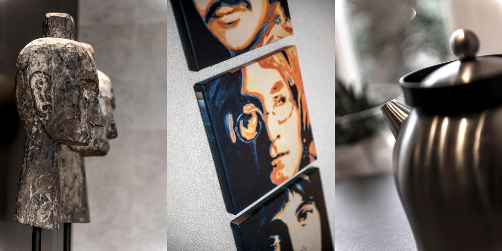 Holzskulpturen, Wandbilder und eine Teekanne sind im Raum zu sehen.