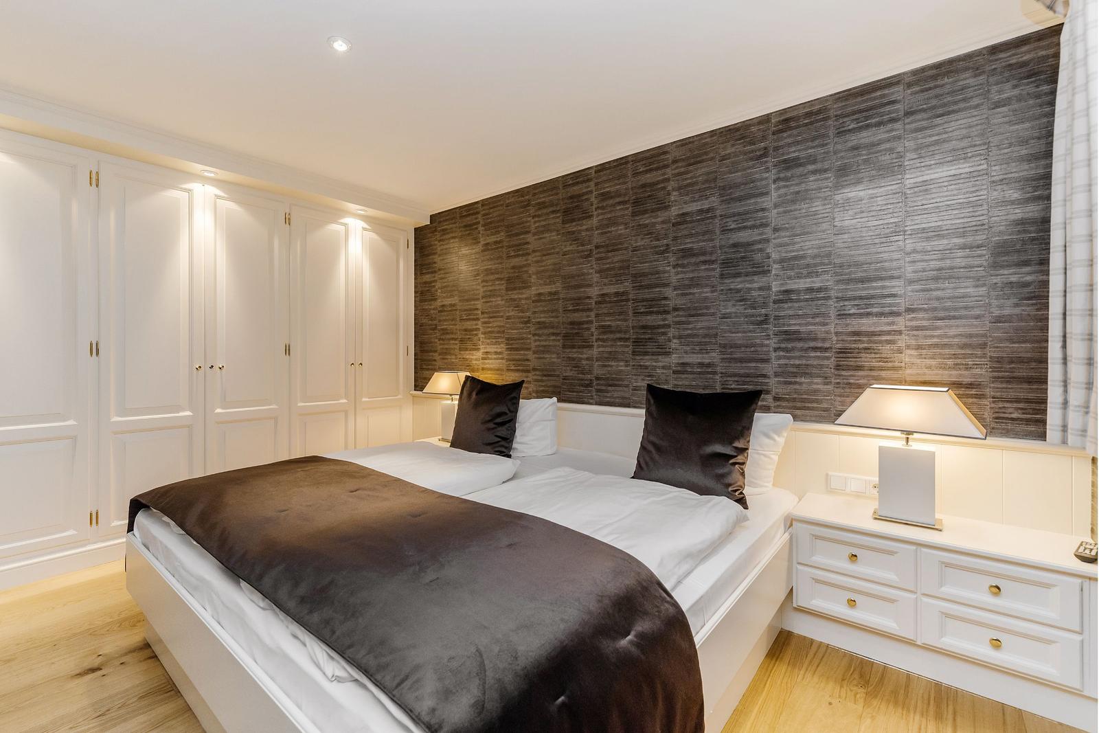 Schlafzimmer mit Bett, Nachttischen und Kleiderschrank.