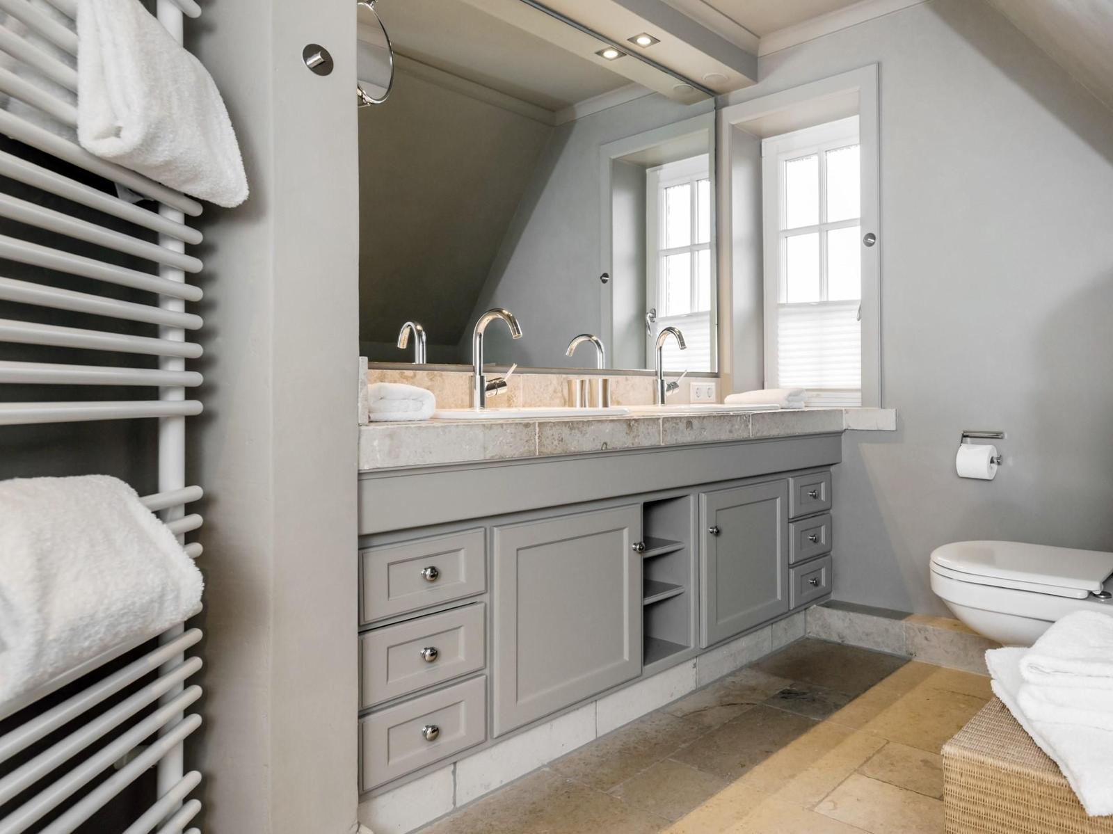 Badezimmer mit Doppelwaschbecken, Spiegelschrank und Heizkörper