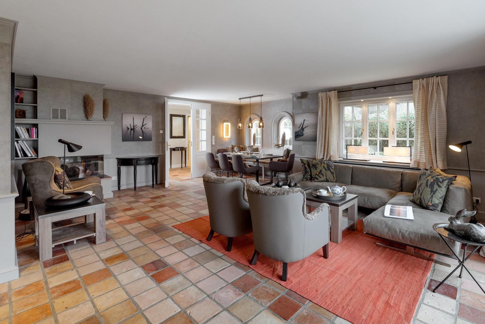 Wohn- und Essbereich mit Kamin, Sitzgruppe und Terrakottboden.