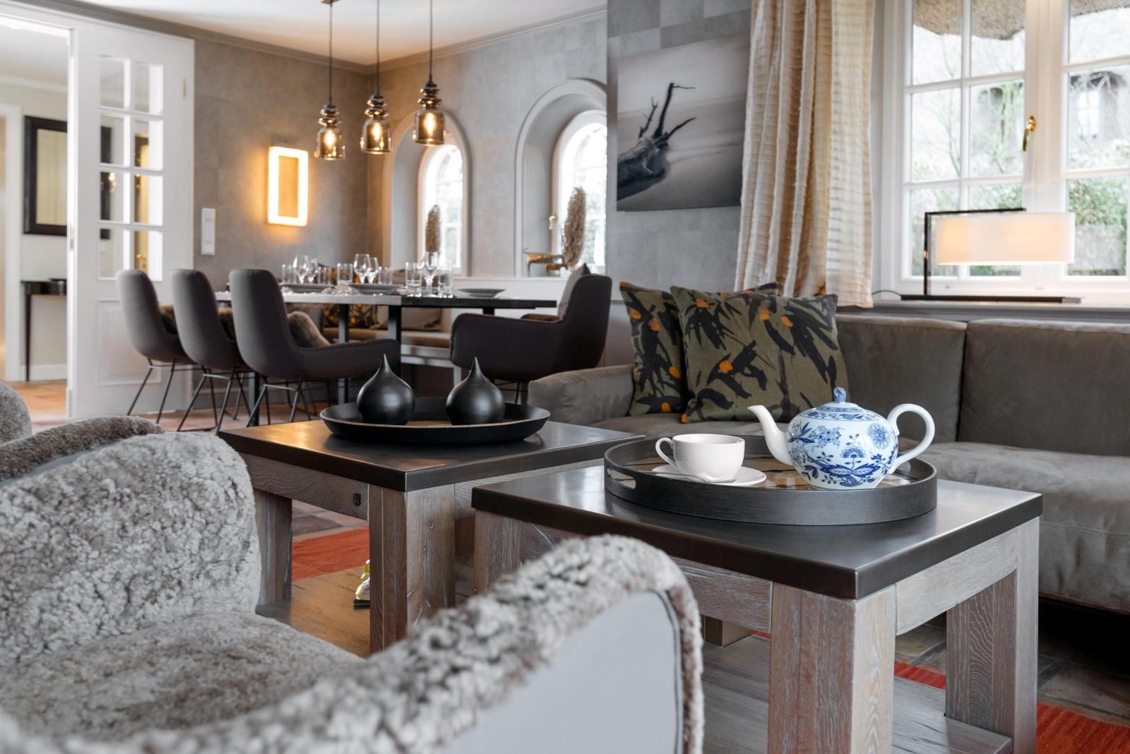 Wohn- und Essbereich mit Sofa, Tischen und Fenstern.