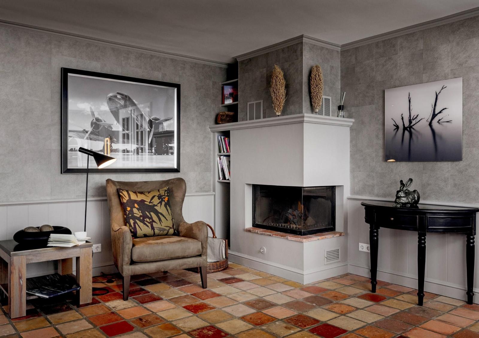 Wohnzimmer mit Kamin, Sessel und dekorativen Bildern an den Wänden.