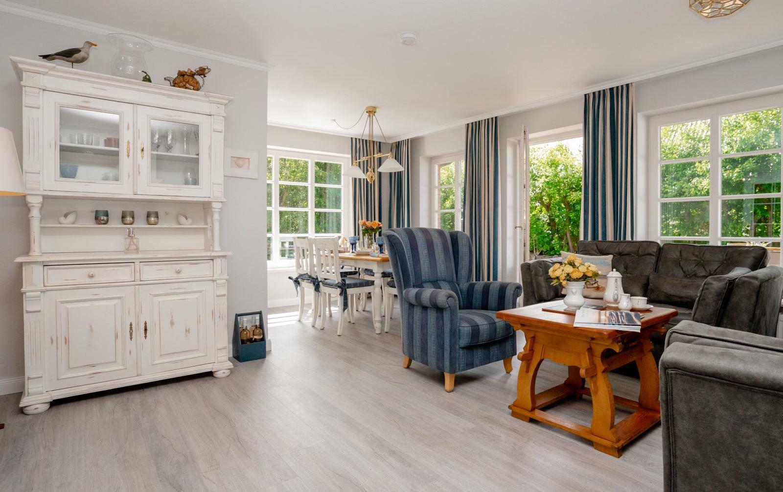 Wohn- und Essbereich mit Sofa, Stuhl und Esstisch. Holzboden und große Fenster.