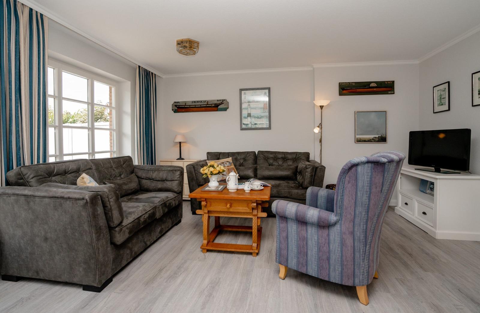 Wohnzimmer mit zwei Sofas, einem Sessel und einem Fernseher.