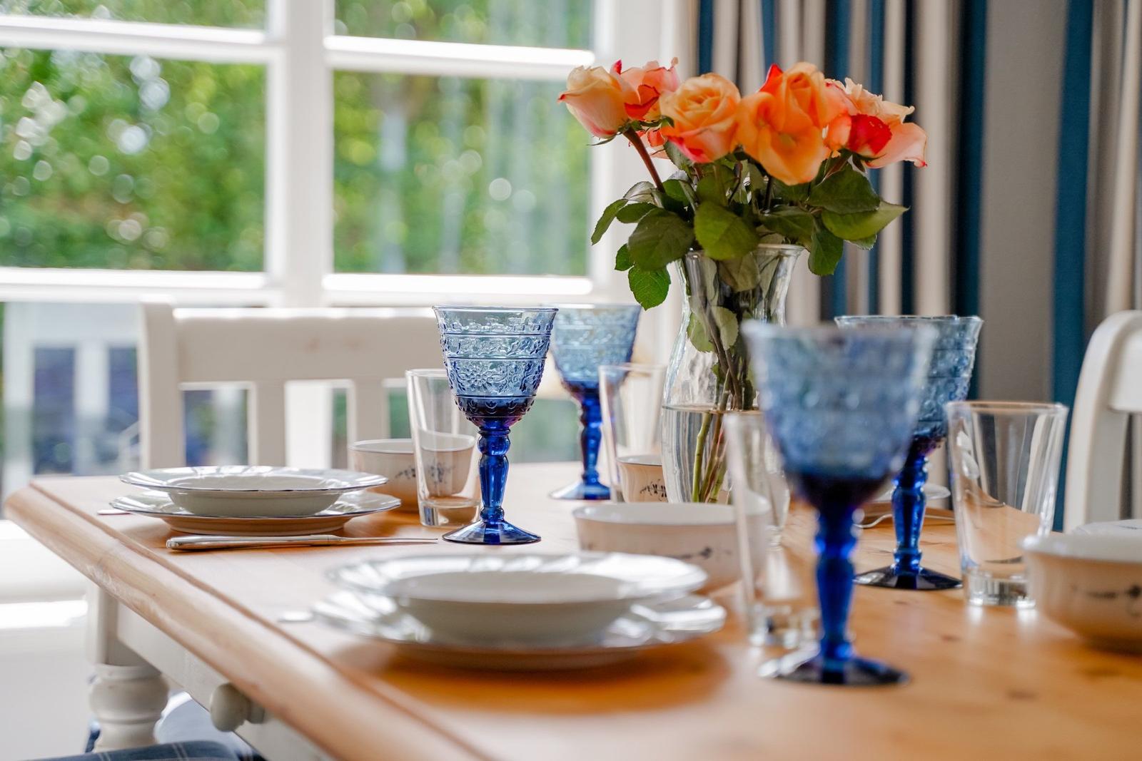 Esszimmertisch mit blauen Gläsern und Rosenstrauß