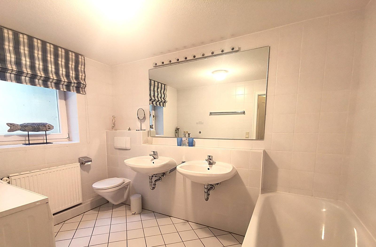 Badezimmer mit zwei Waschbecken, Badewanne und Toilette.