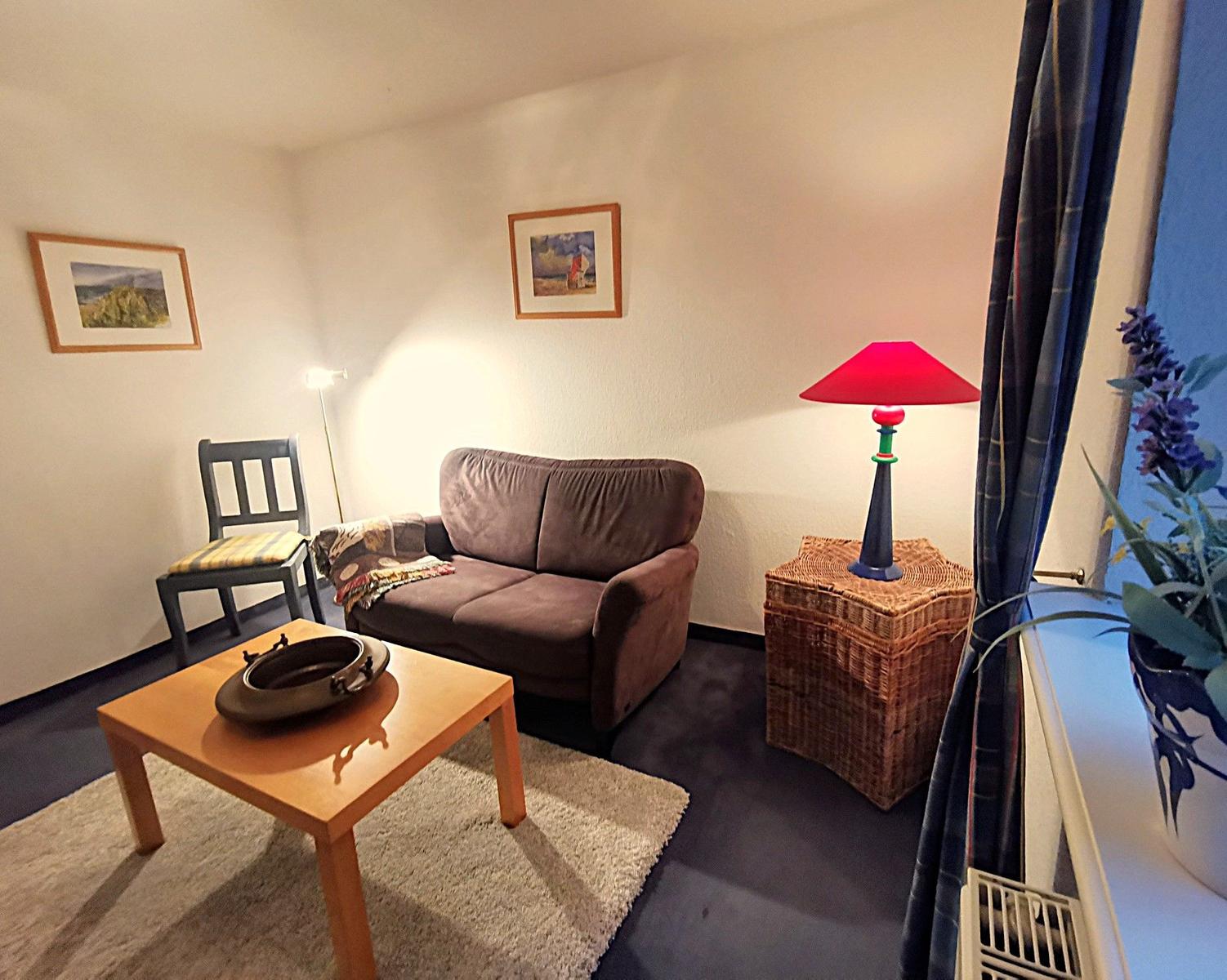 Ein Wohnzimmer mit Sofa, Stuhl, Tisch und Lampe.