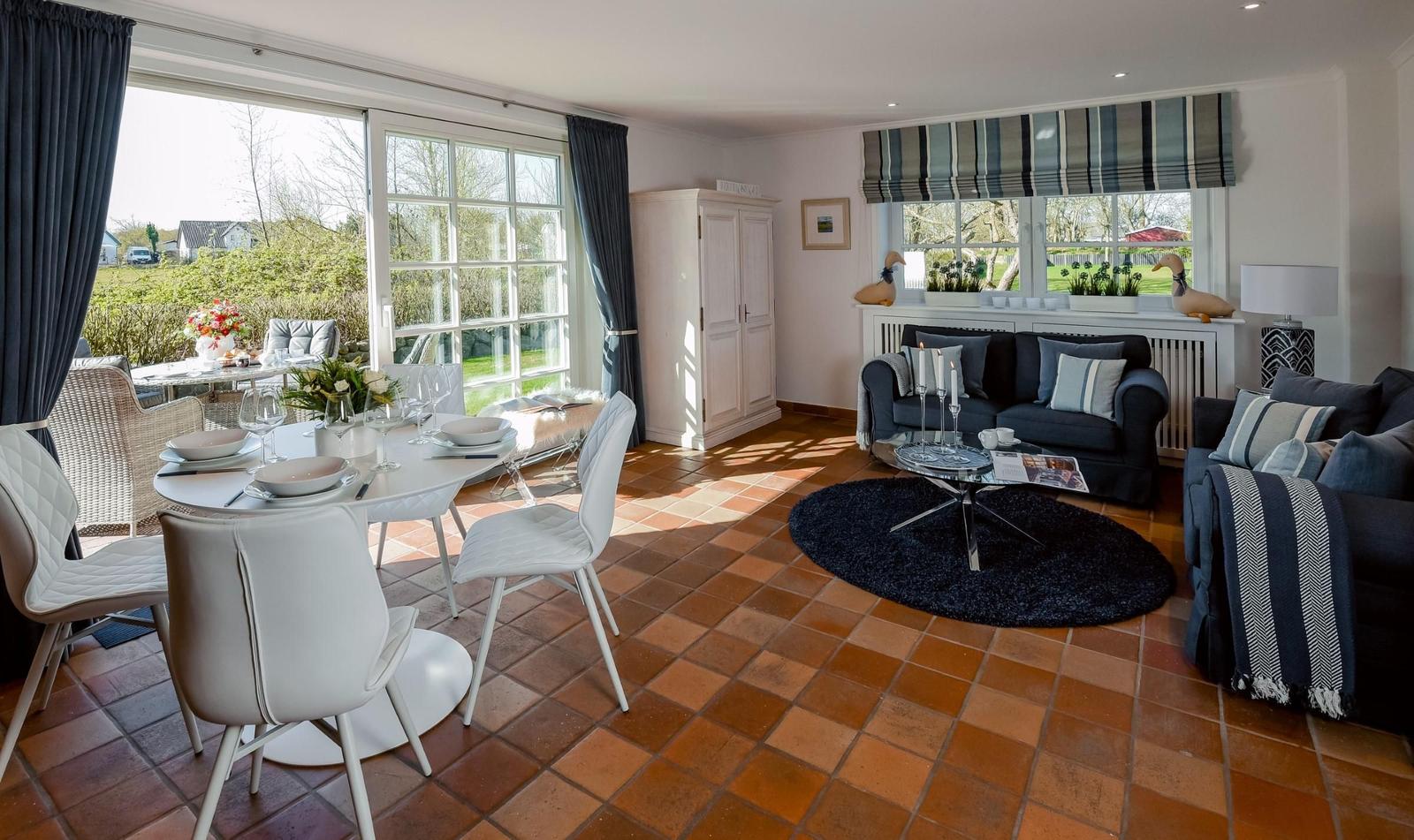 Ein Esszimmer mit Tisch und Stühlen, ein Wohnbereich mit Sofa und Couch, Terrasse mit Blick auf Garten.