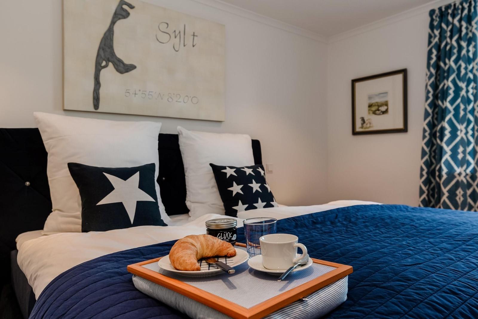 Schlafzimmer mit Bett, Kissen und Frühstückstablett.