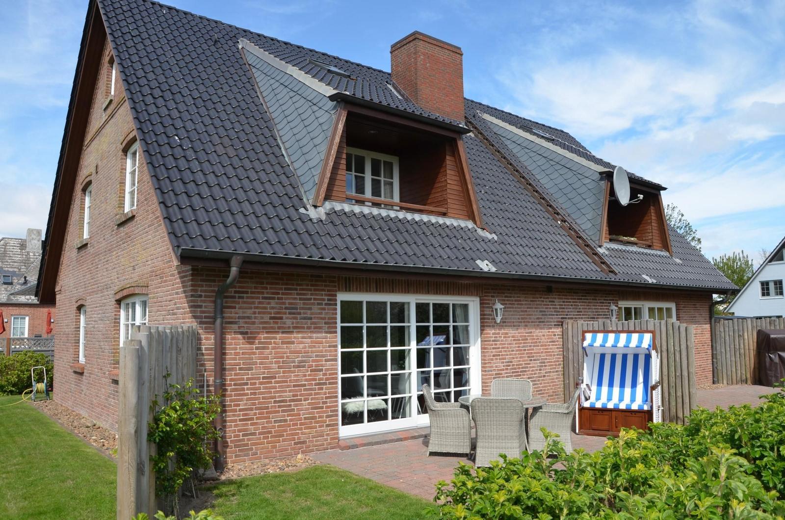 Rotes Backsteinhaus mit Terrasse und Strandkorb. Dach mit Schiefer und Dachfenstern.