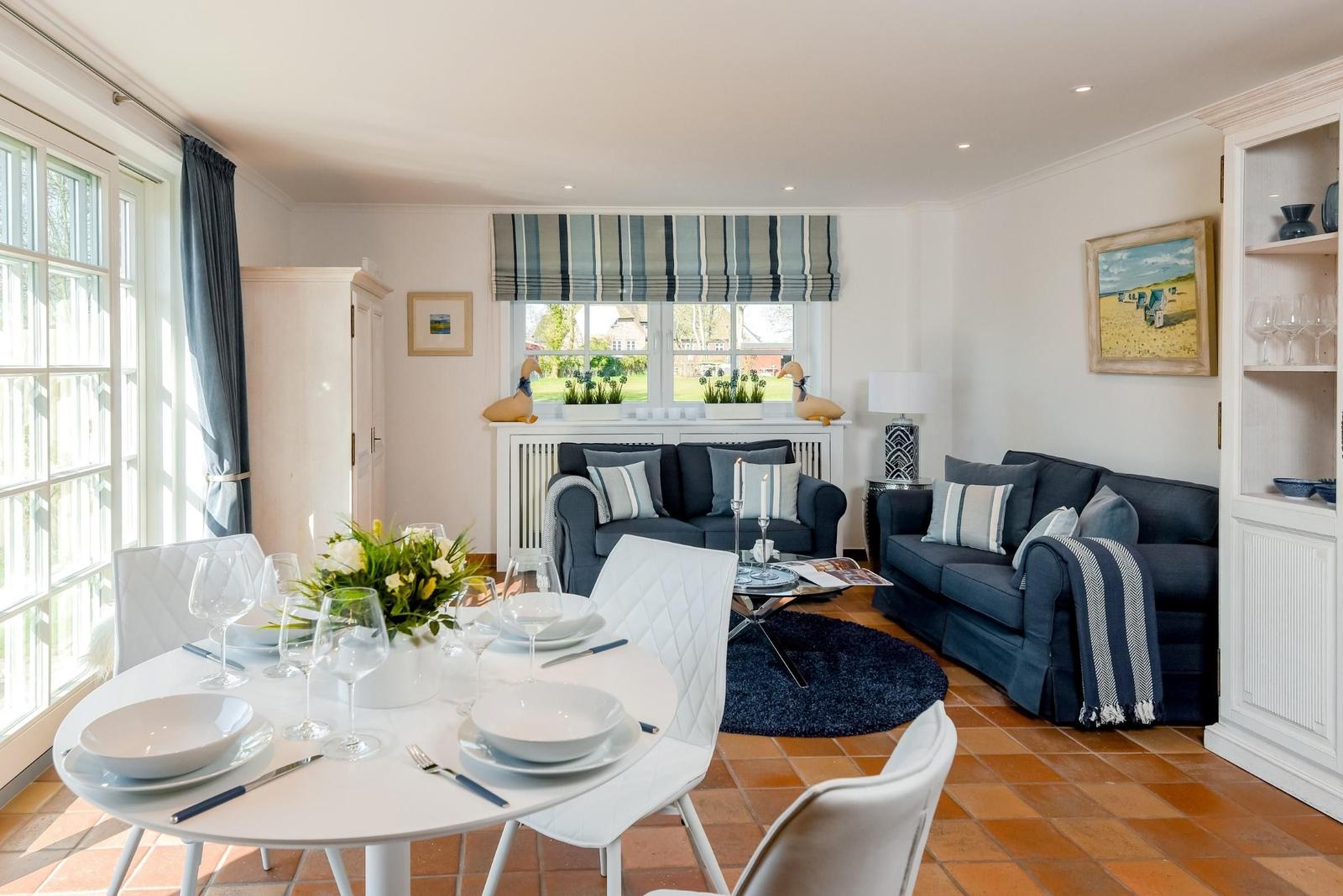 Essbereich mit Tisch und Stühlen. Wohnbereich mit Sofa und Fenster.