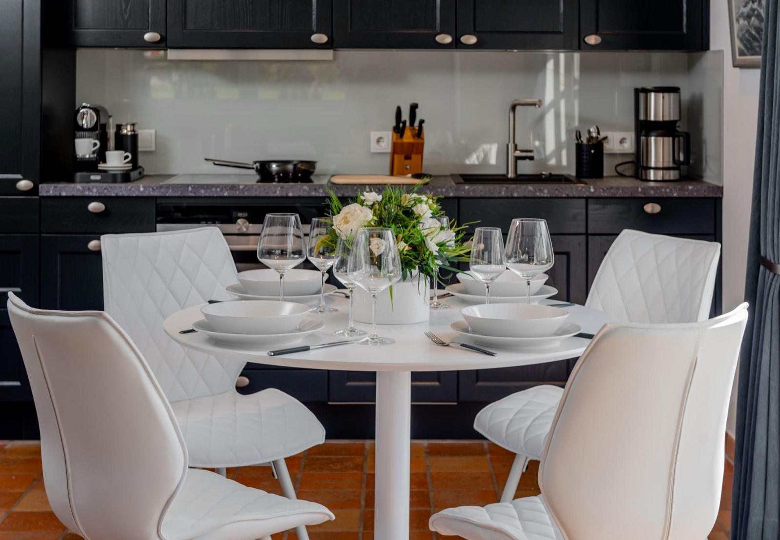 Runder Tisch mit weißen Stühlen und Geschirr in moderner Küche.