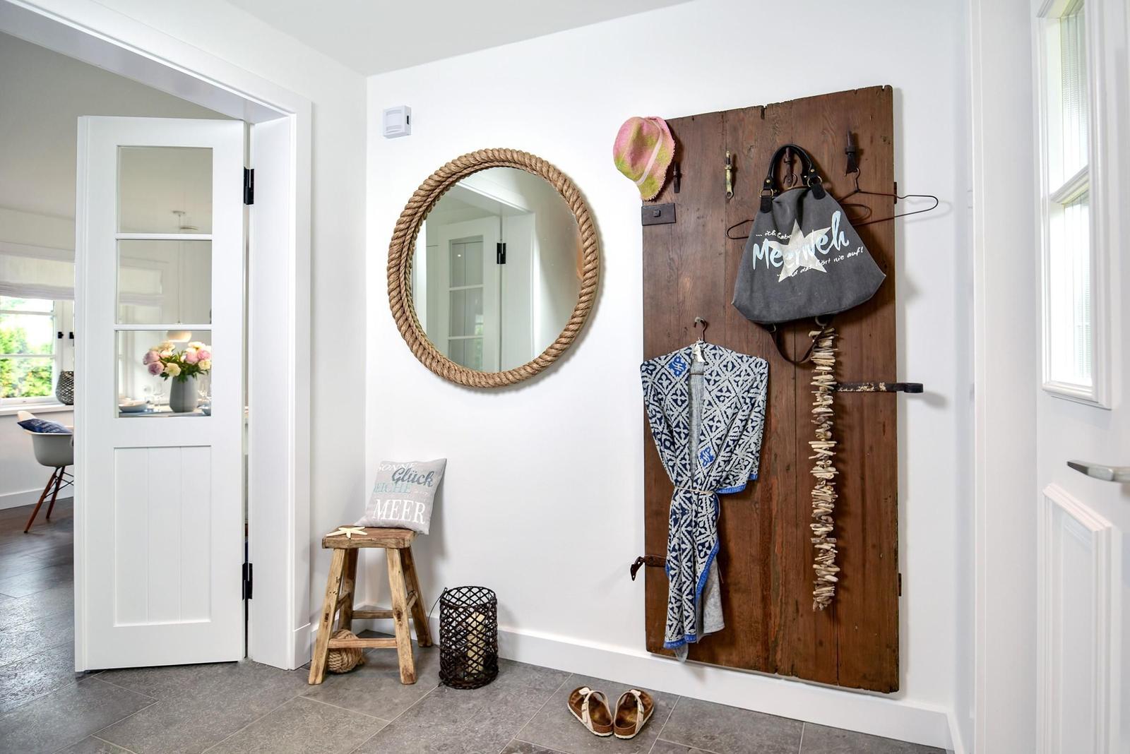 Eingangsbereich mit Spiegel, Stuhl und Holzpaneel mit Kleidung.