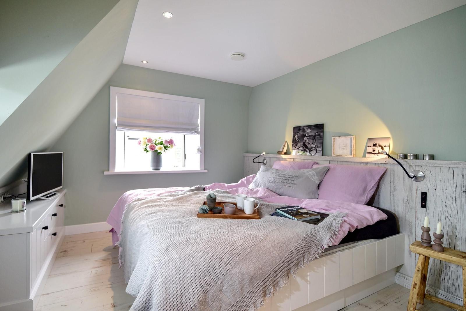 Schlafzimmer mit Bett, Fenster und Fernseher an der Wand.