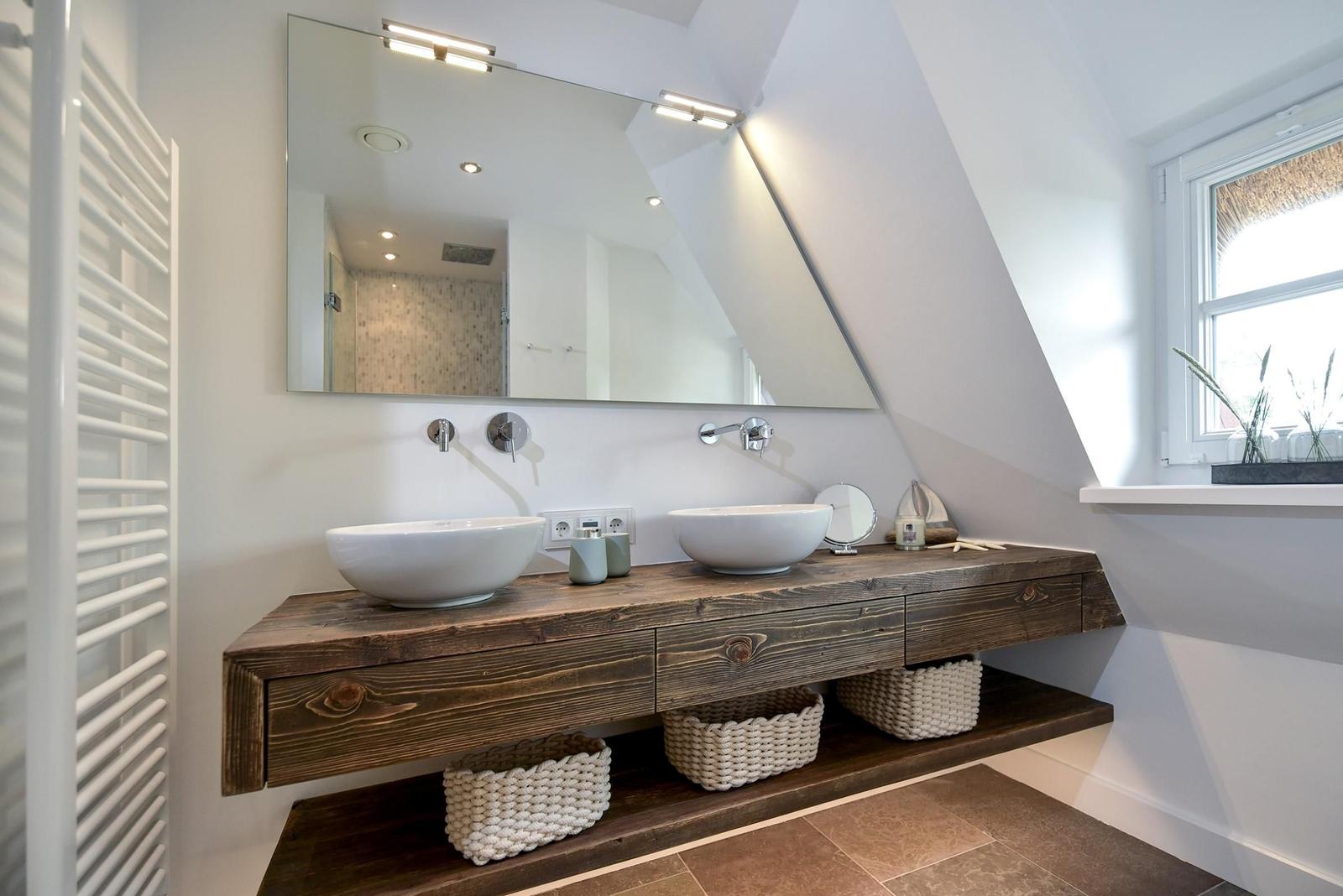 Badezimmer mit Holzwaschtisch, zwei Waschbecken und Spiegel unter Dachschrägen.