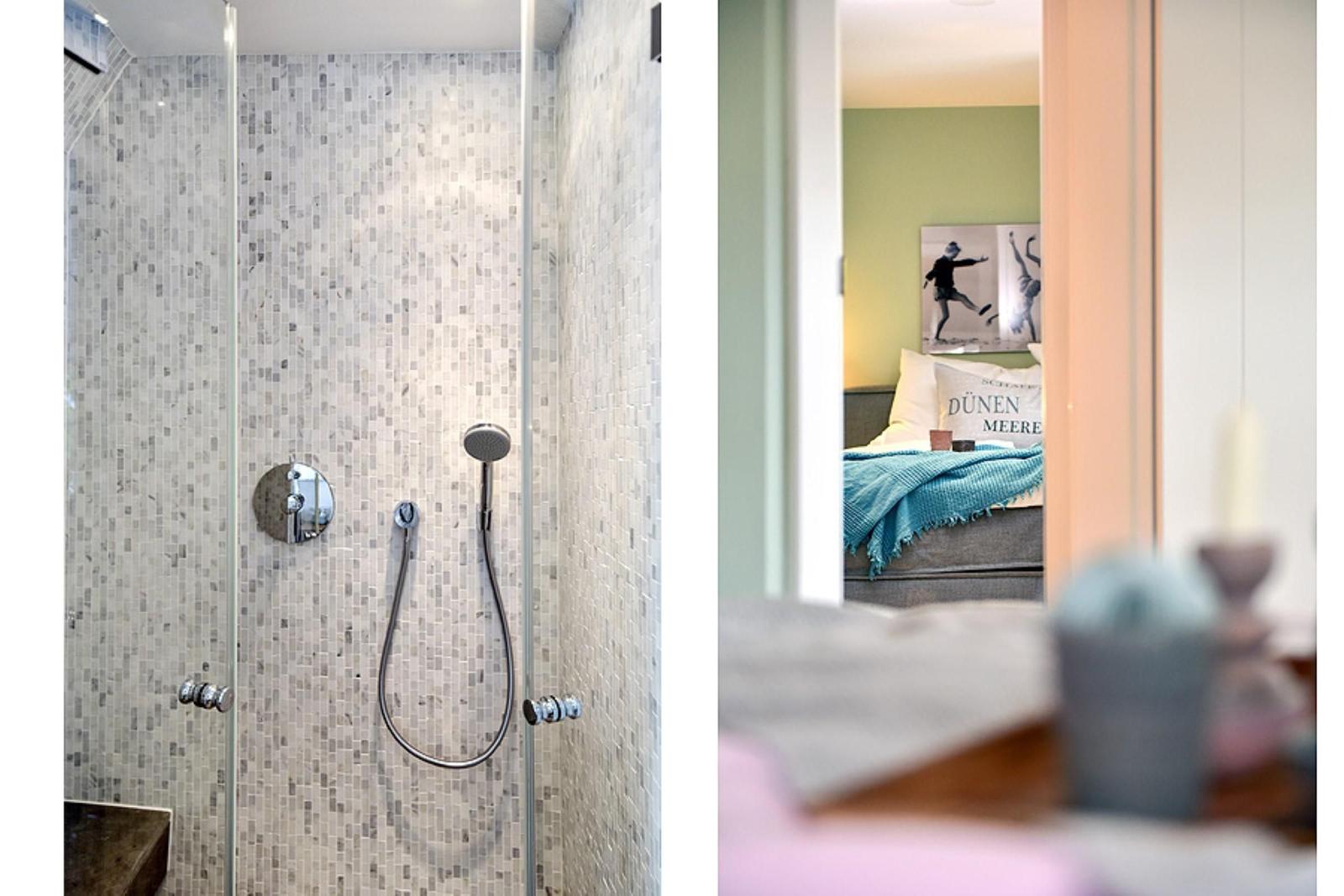 Dusche mit Mosaikwand und Handbrause. Schlafzimmer mit Bett und Wandbild.