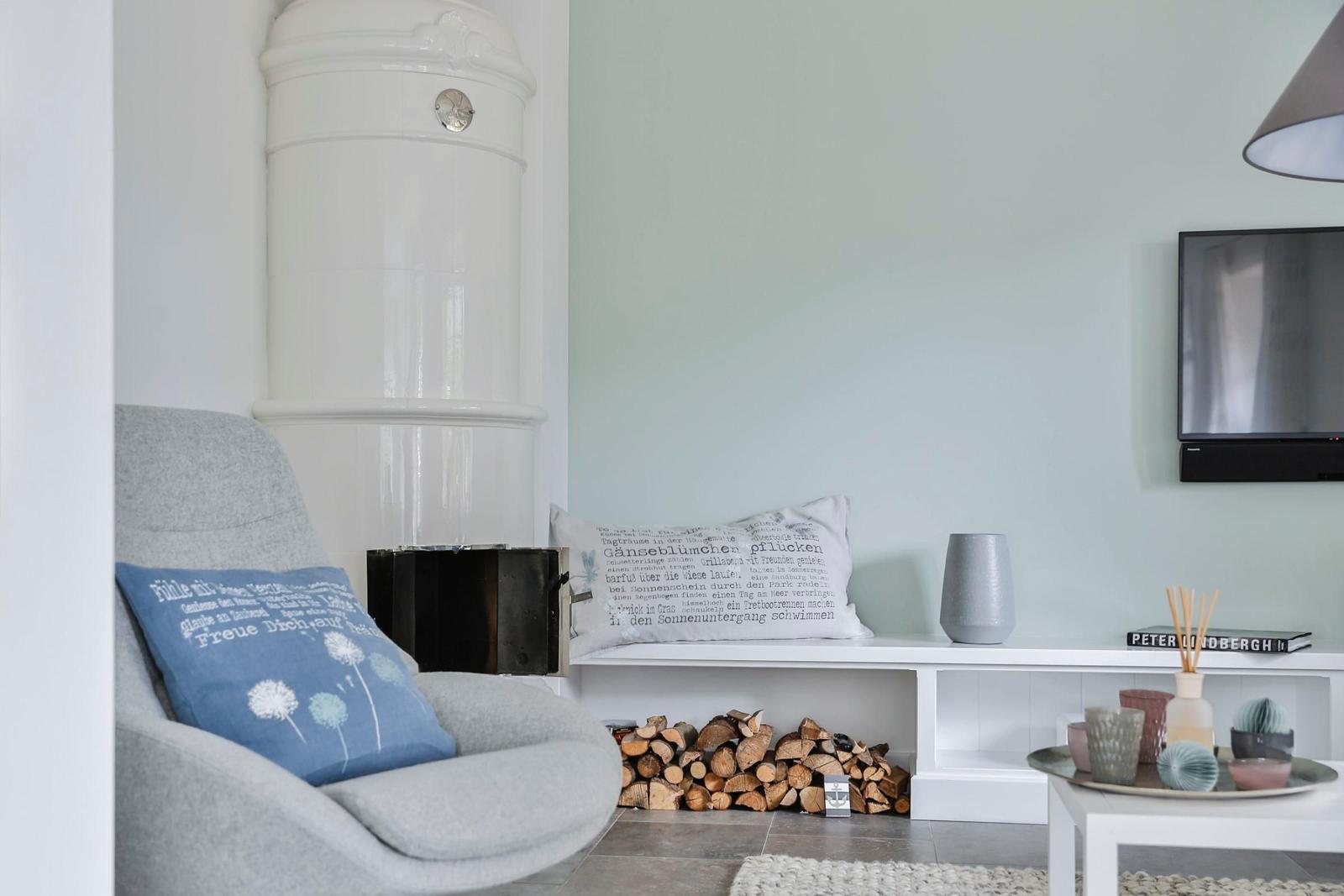 Ein Wohnzimmer mit grauer Sitzgelegenheit, Kamin und Fernseher an der Wand.