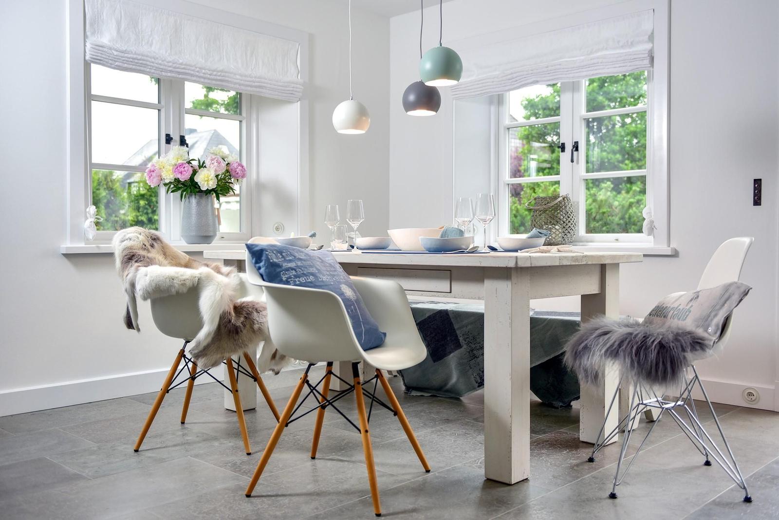 Esszimmer mit Tisch, Stühlen und Fenstern mit Blick auf Grün.