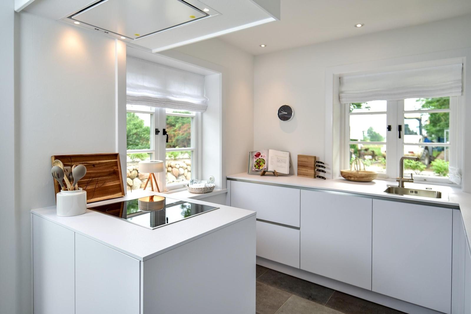 Moderne Küche mit weißen Schränken, Fenstern und Kücheninsel.