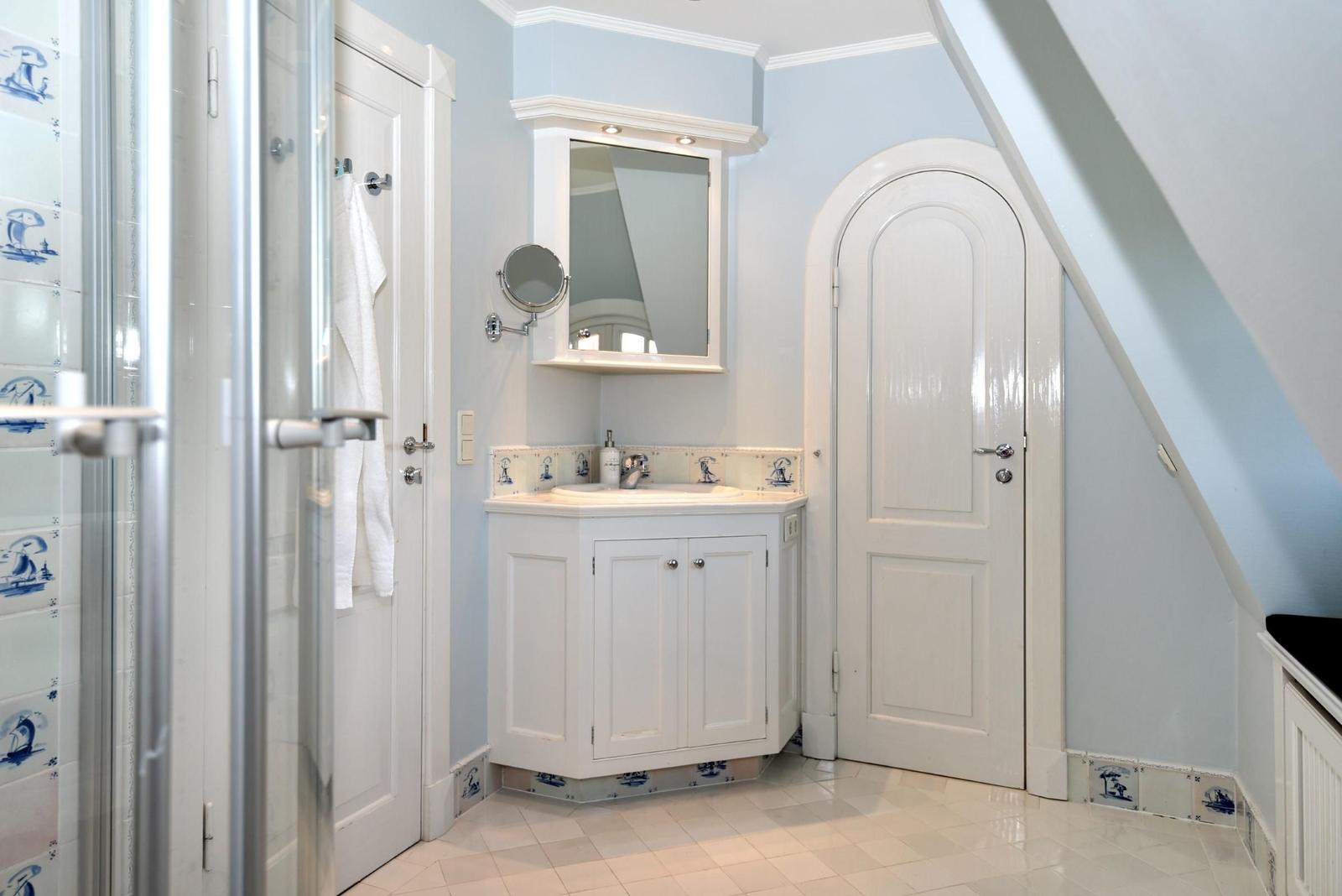 Badezimmer mit Duschabtrennung, Waschbecken und Spiegelschrank.