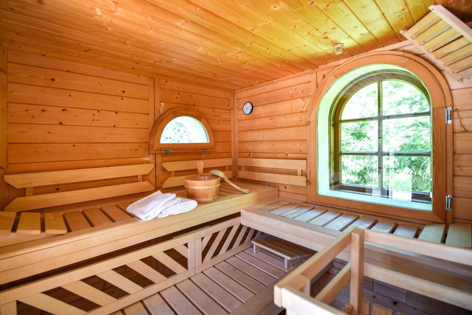 Holzsauna mit Sitzbänken, Fenster und Holzbadewanne.