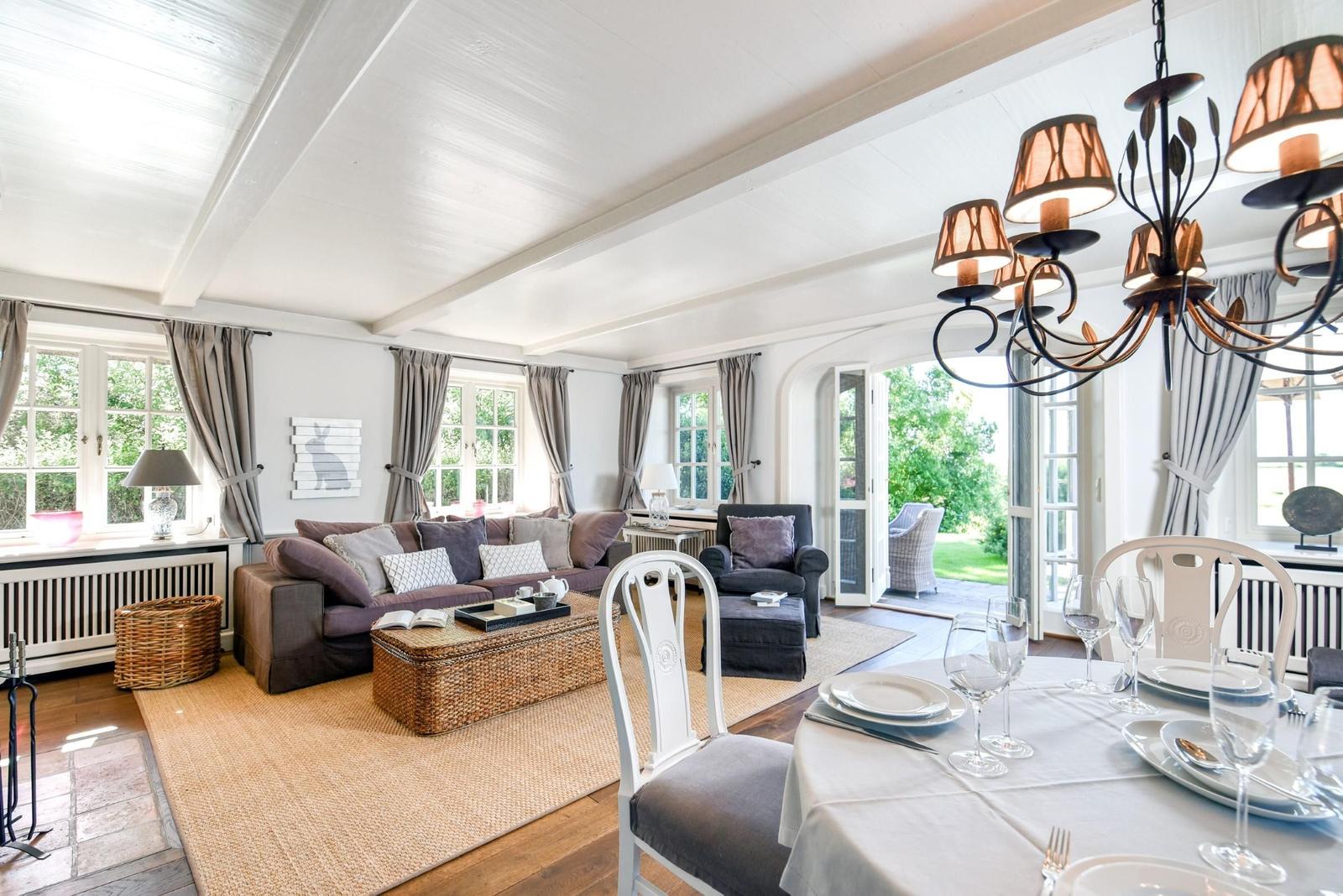 Wohn- und Essbereich mit Sofa, Tisch und Kronleuchter.