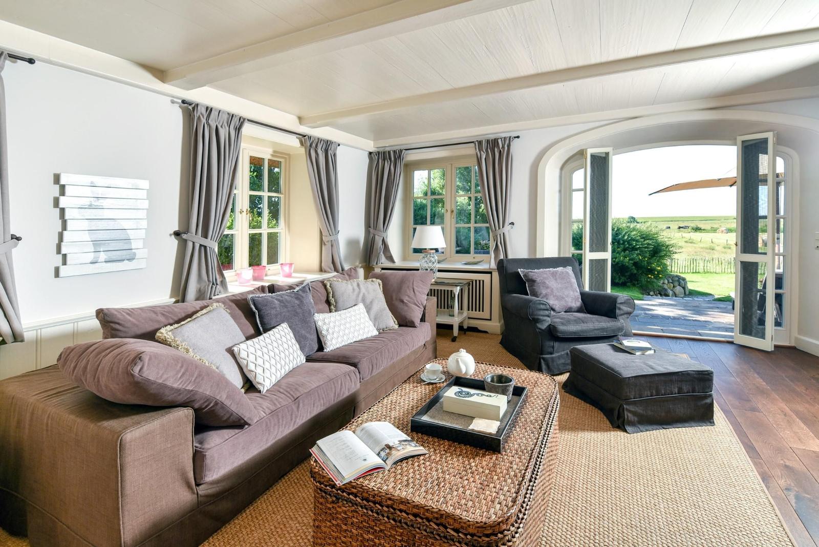 Wohnzimmer mit Sofa, Sessel und Blick auf Garten.