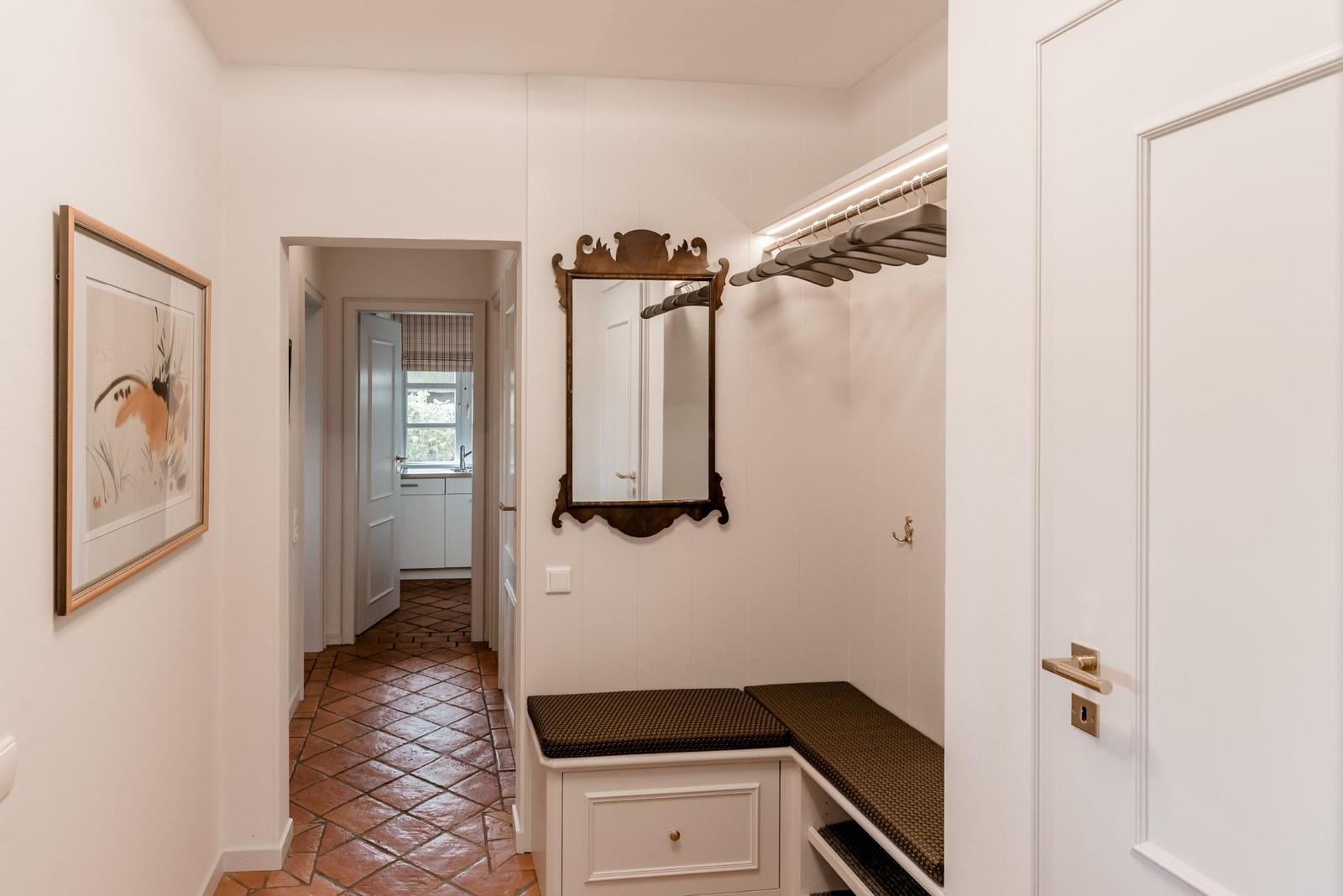 Entrance area with closet, mirror, and picture on the wall. Hallway leads to the kitchen.