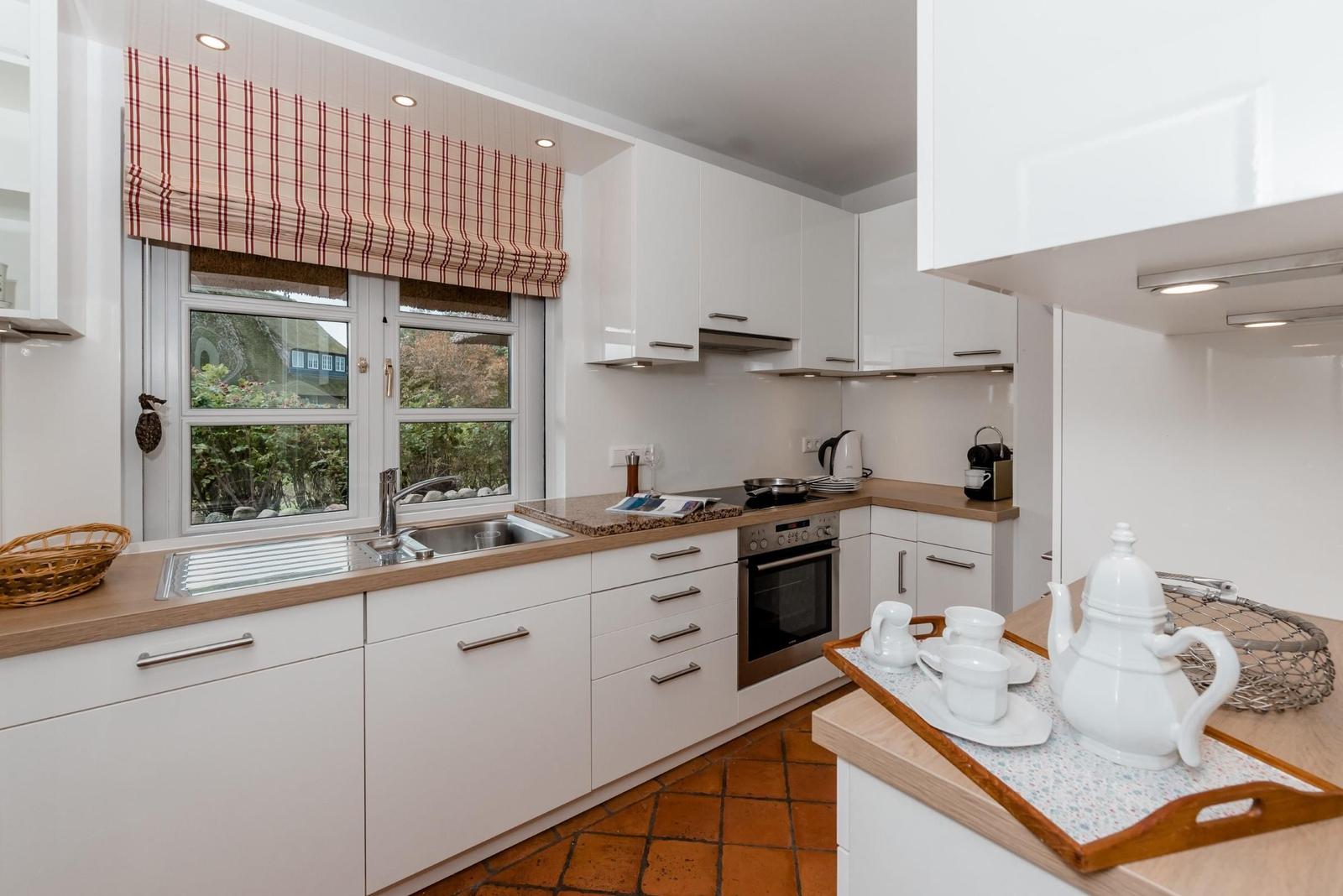 Kitchen with white cabinets, wooden surfaces, and red window shade.