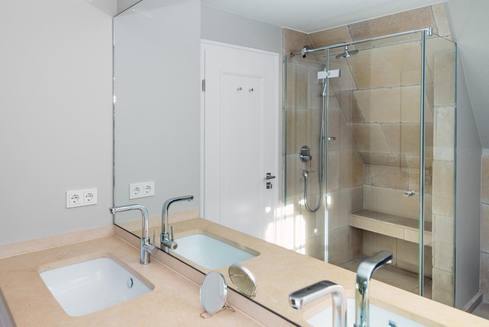 Badezimmer mit Dusche, Waschbecken und Spiegel