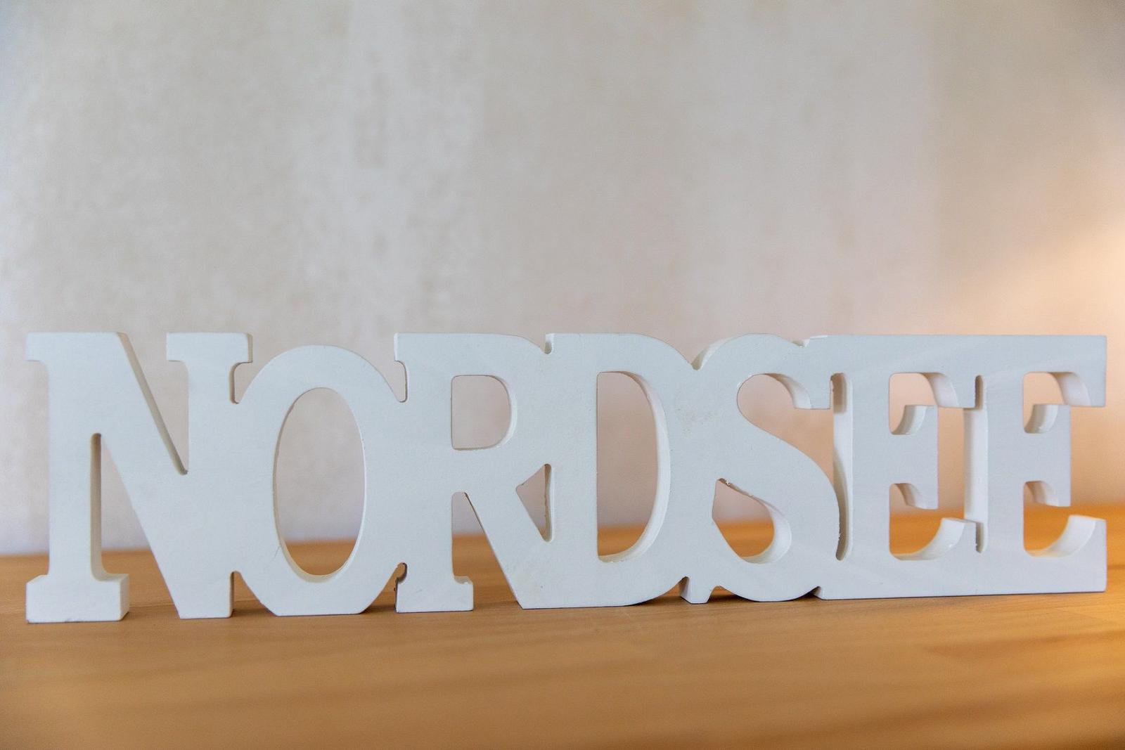 Weißes Schriftzug-Nordsee-Objekt auf Holzoberfläche