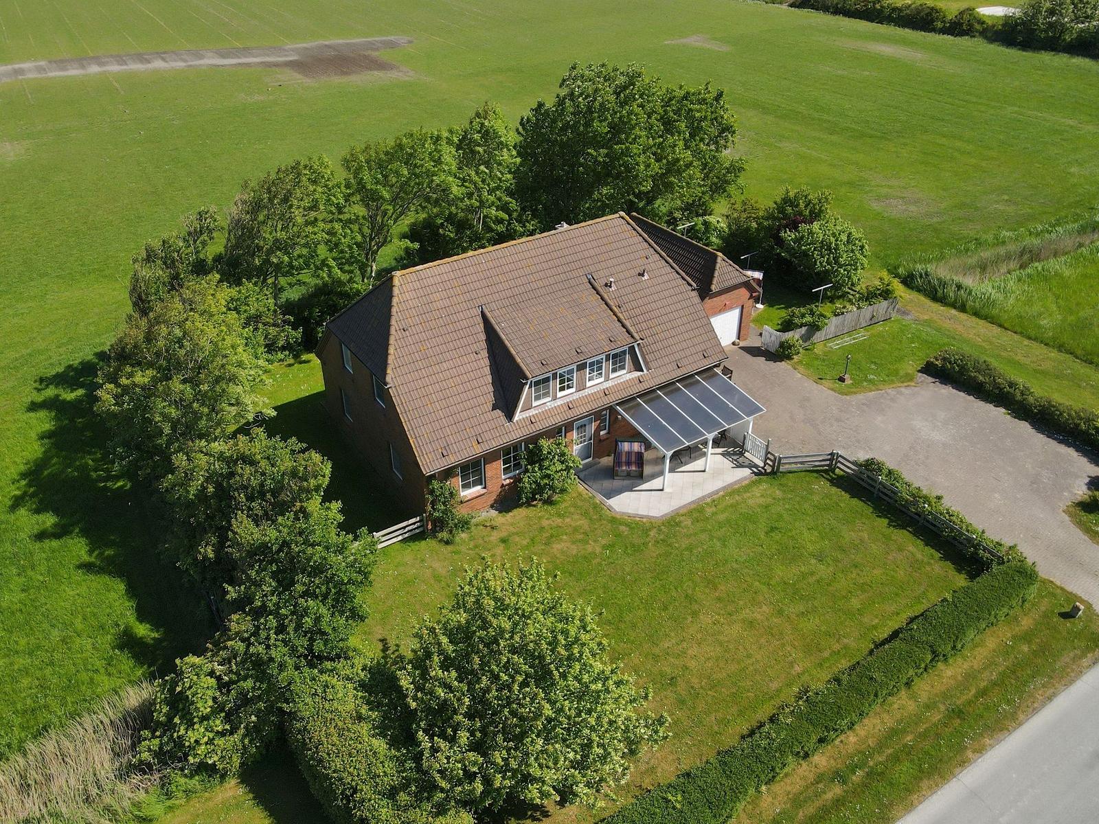 Haus mit Terrasse, Garten und umliegenden Feldern.
