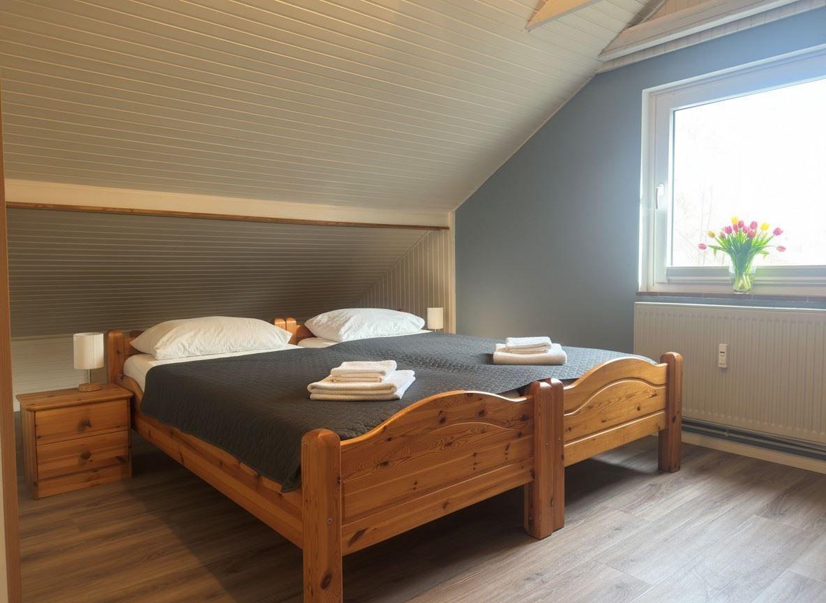 Schlafzimmer mit Holzbett, Fenster und Blumen