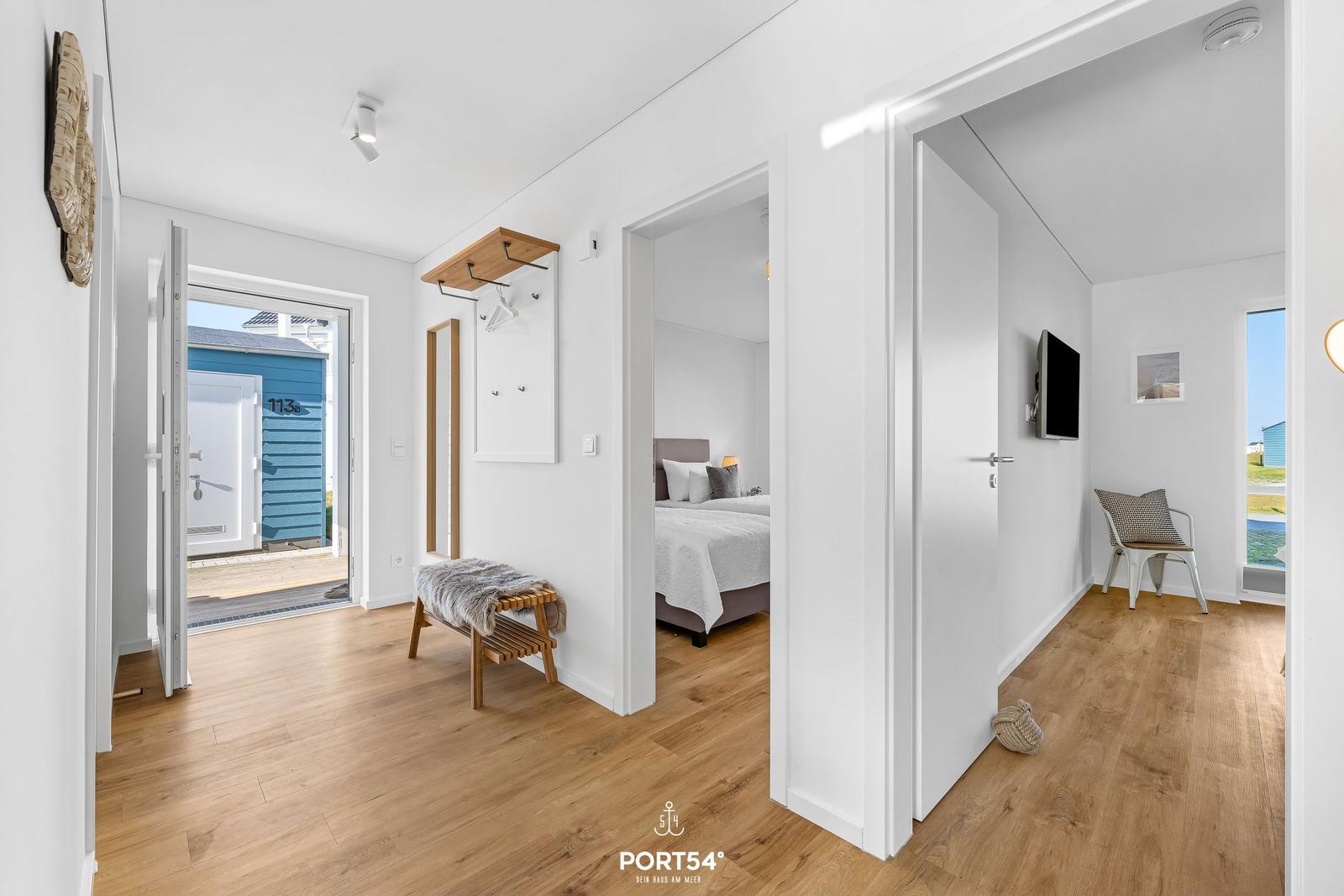 Haus mit Eingangsbereich, Schlafzimmer und Wohnbereich mit Holzboden und weißen Wänden.