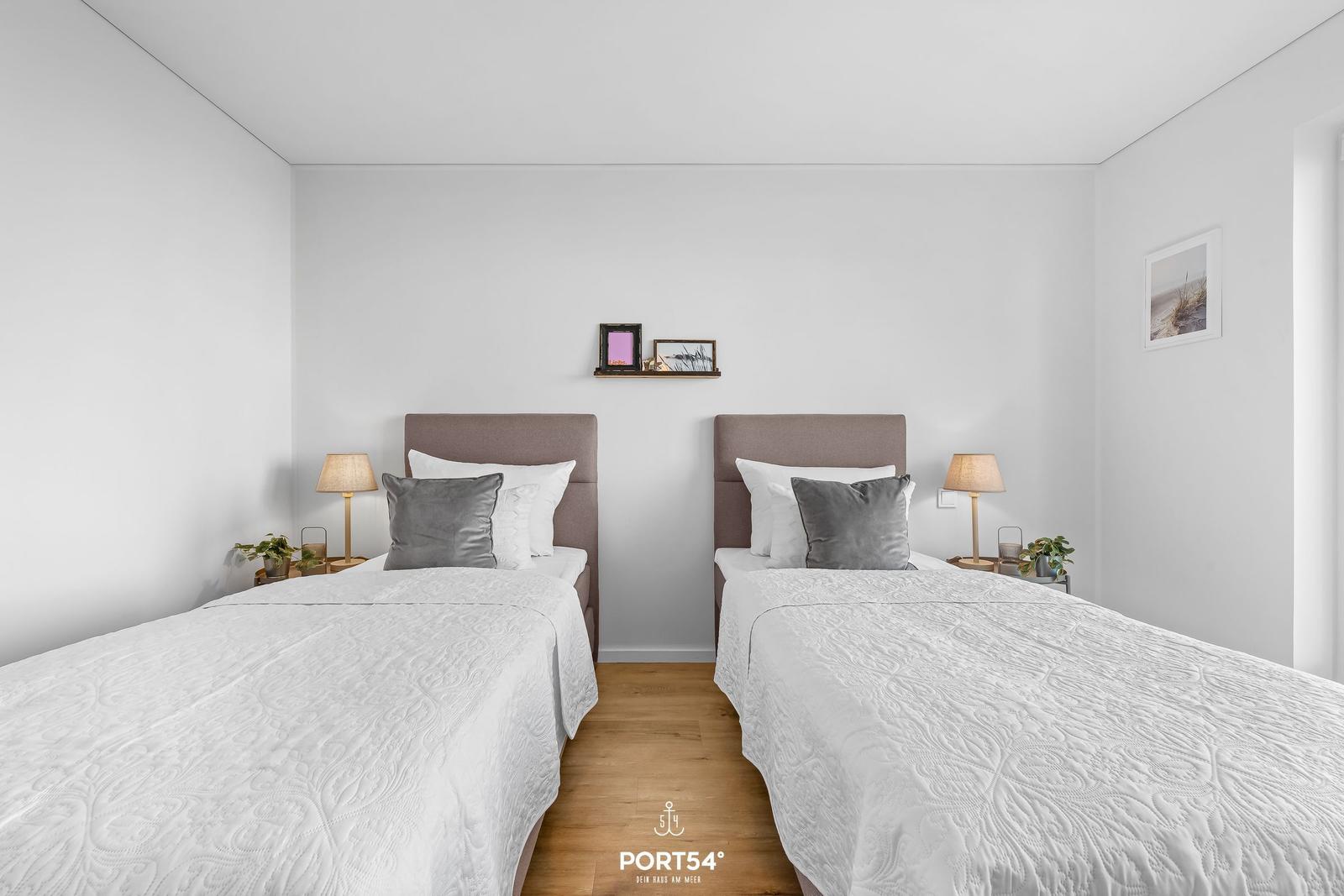 Zwei Schlafzimmer mit weißen Bettwäschen und Holzboden.